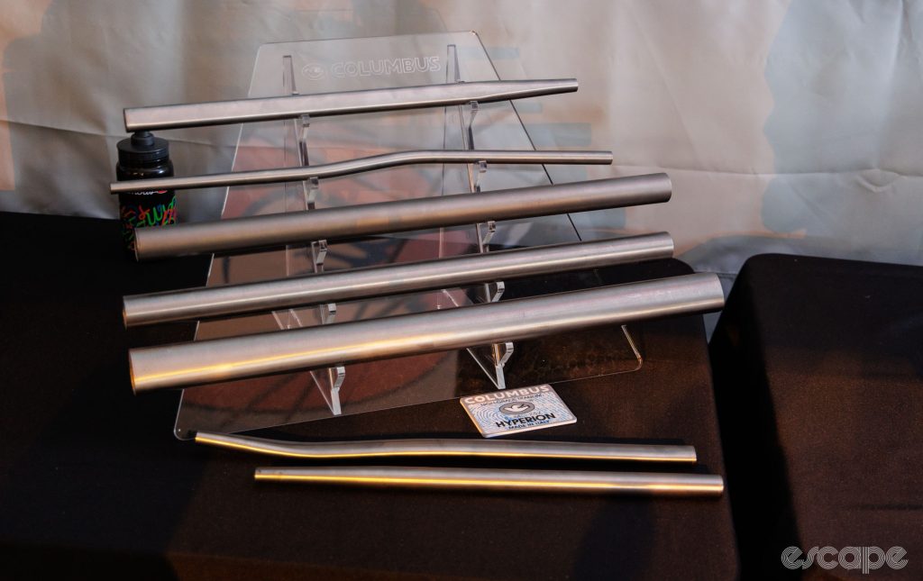 Raw titanium tubes sit on a display rack. 