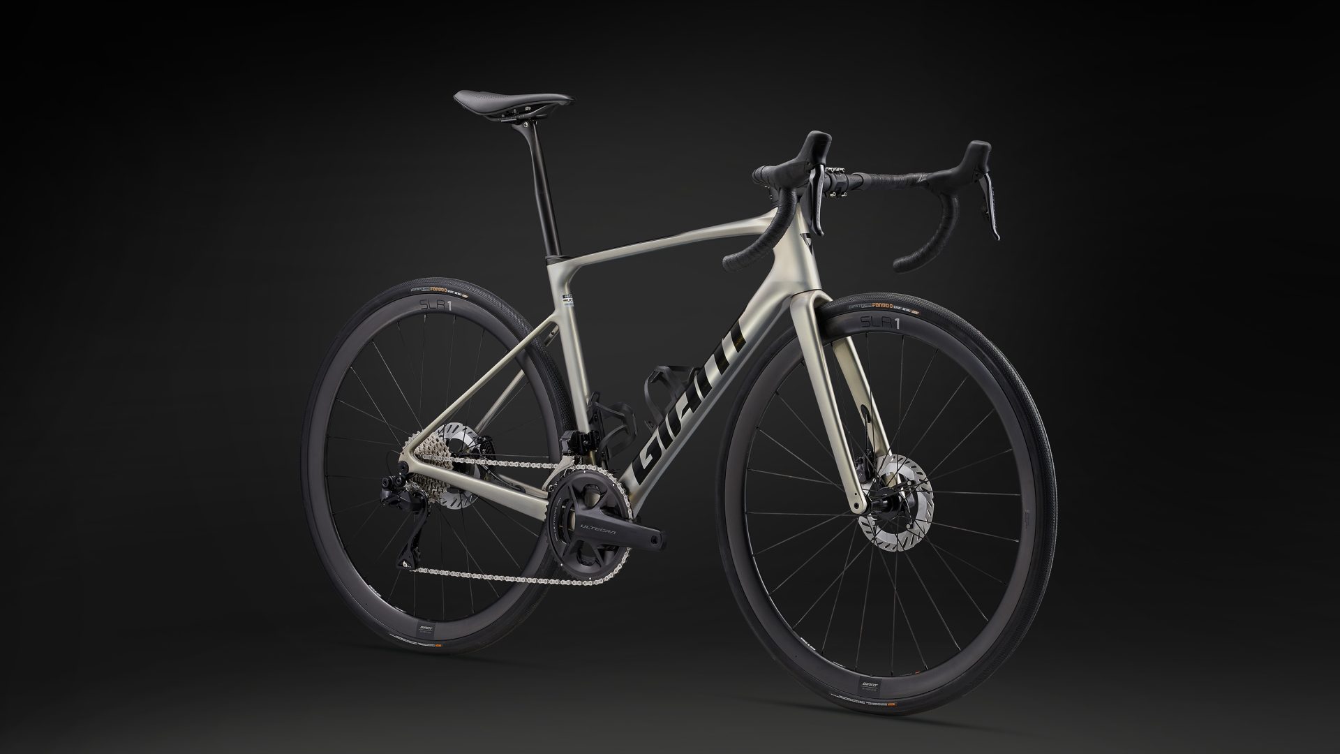 The 2024 Giant Defy Advanced SL 1 in front-quarter profile, shown in a goldish-tan paint and black decals.