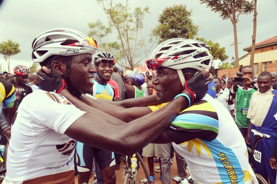 Two Rwandan cyclists embrace.