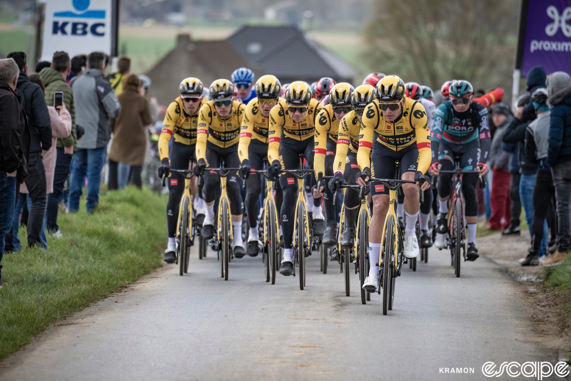 A line of seven Jumbo riders leads the pack at the 2023 Het Nieuwsblad race. They're fanned out in an echelon and almost no other team is even visible at the front of the field.