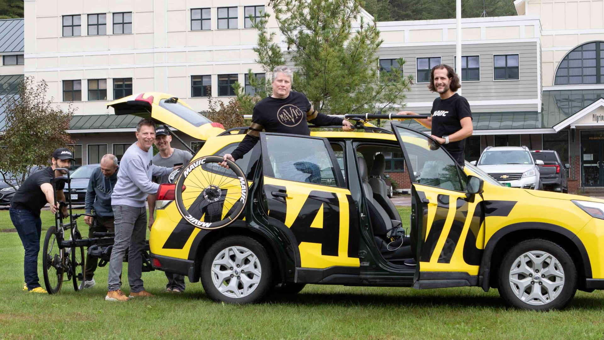 Mavic North America staff standing in front of yellow Mavic team car