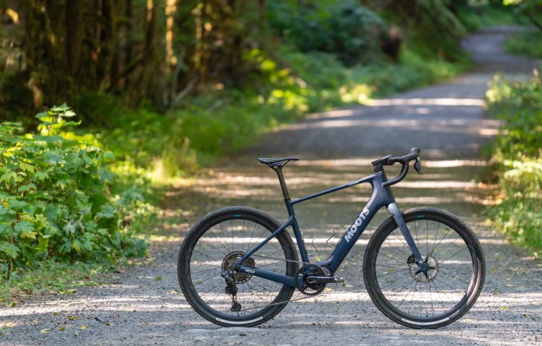 Side profile of Moots Express e-gravel bike on gravel path in the woods