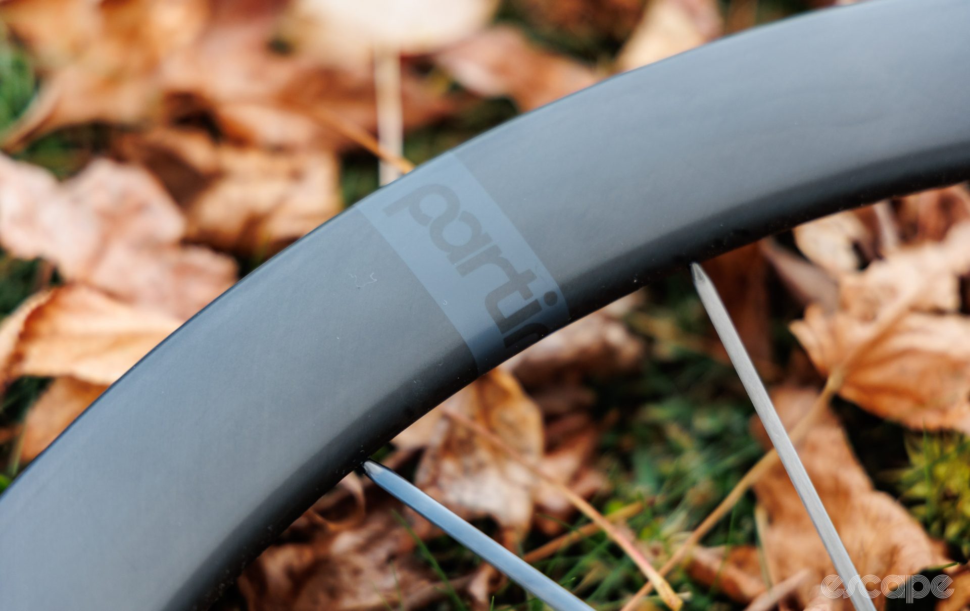 The rim on the Partington MKII is painted a matte black that is thin enough to still let some of the carbon weave texture underneath show through. A subtle charcoal grey and black decal is the only branding.