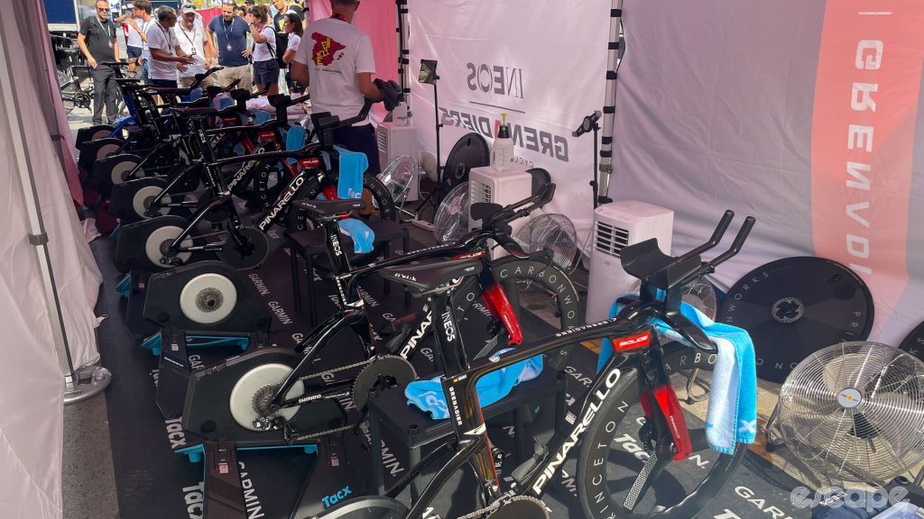 The photo shows inside the Ineos Grenadiers cool tent from another angle. We can see the team bikes on stationary trainers with fans and air conditioning units in front of each ride.