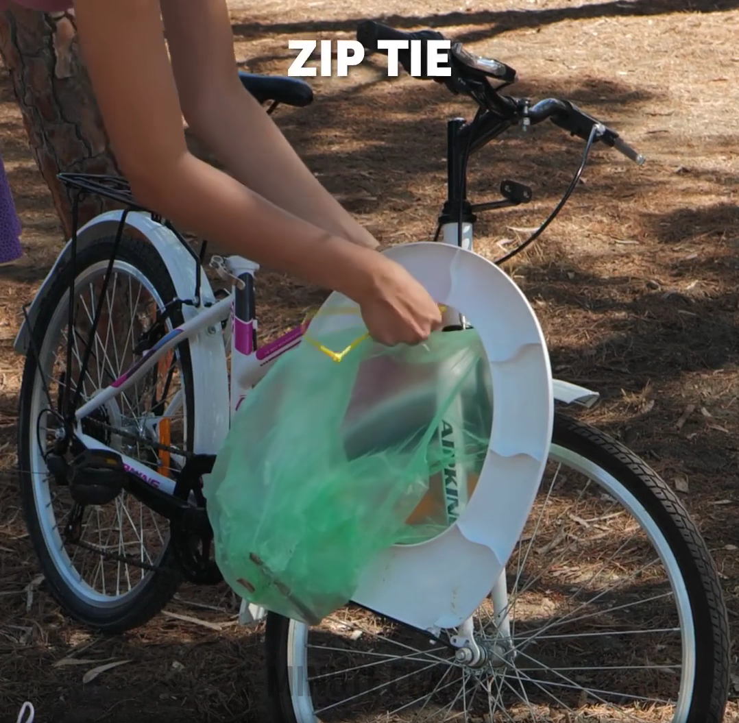 Someone attaches a toilet seat with a plastic bag beneath it to the side of a bike.