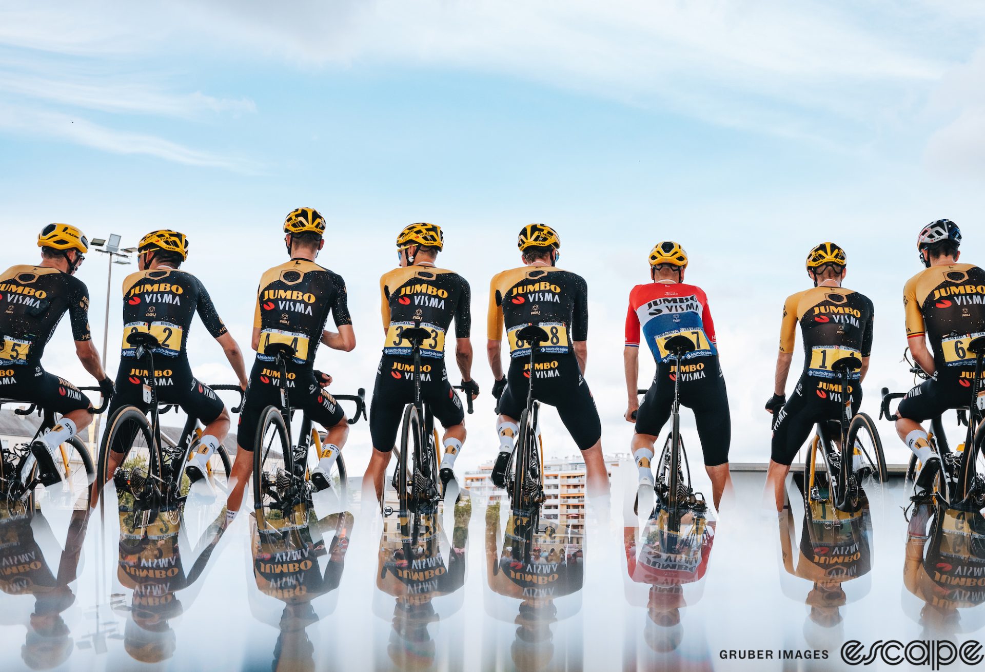 The Jumbo-Visma team attends sign-in at the start of stage 6 of the 2023 Tour de France. Their images are shown in reflection to create a mirror effect.