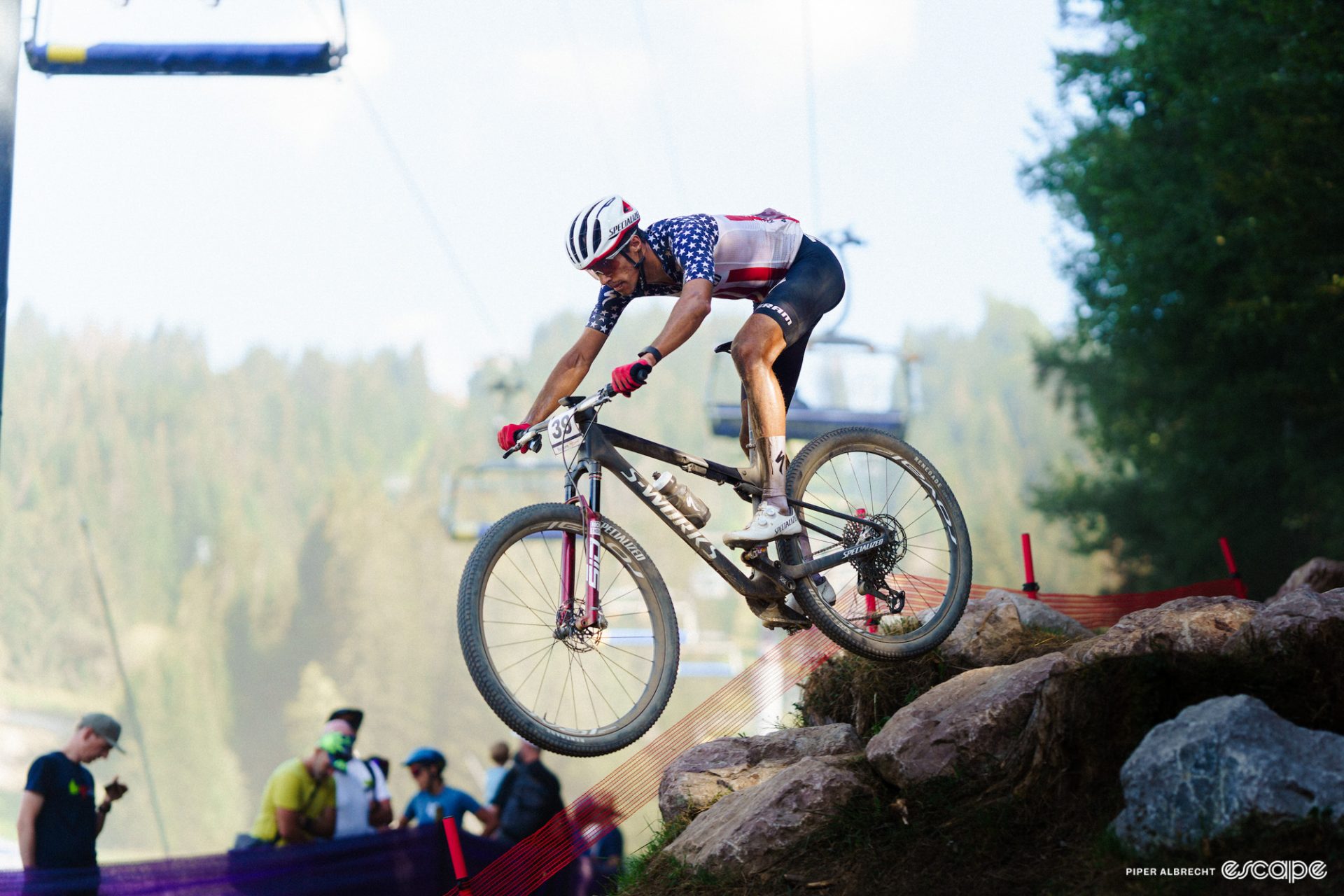 Blevins launches a rock drop at a World Cup. He's fully in the air, arms extended as he pushes the bike out and down over a rocky dropoff in anticipation of the landing.