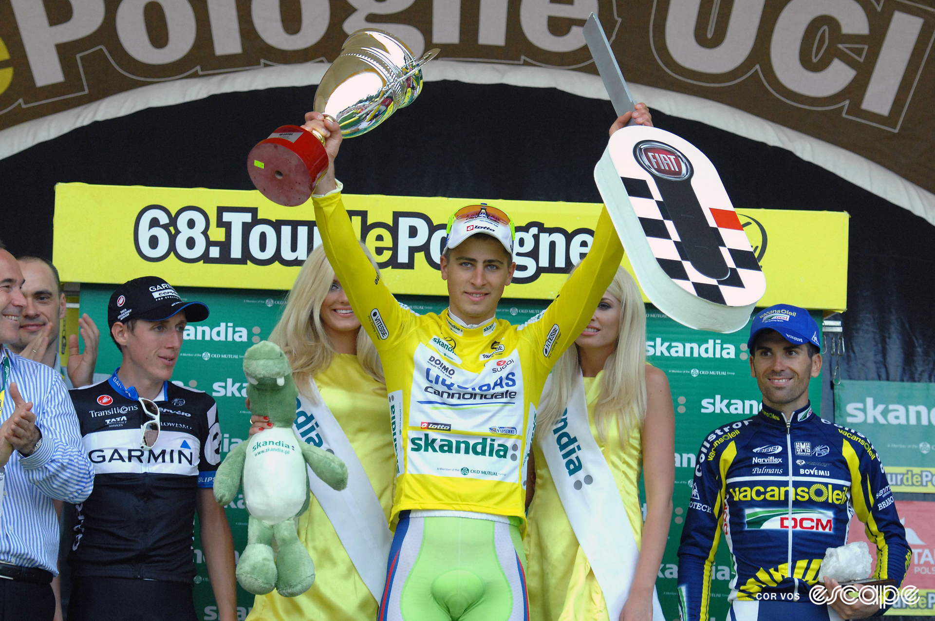 Peter Sagan stands on the podium at the Tour of Poland, holding a trophy and a strange, guitar-like object aloft.