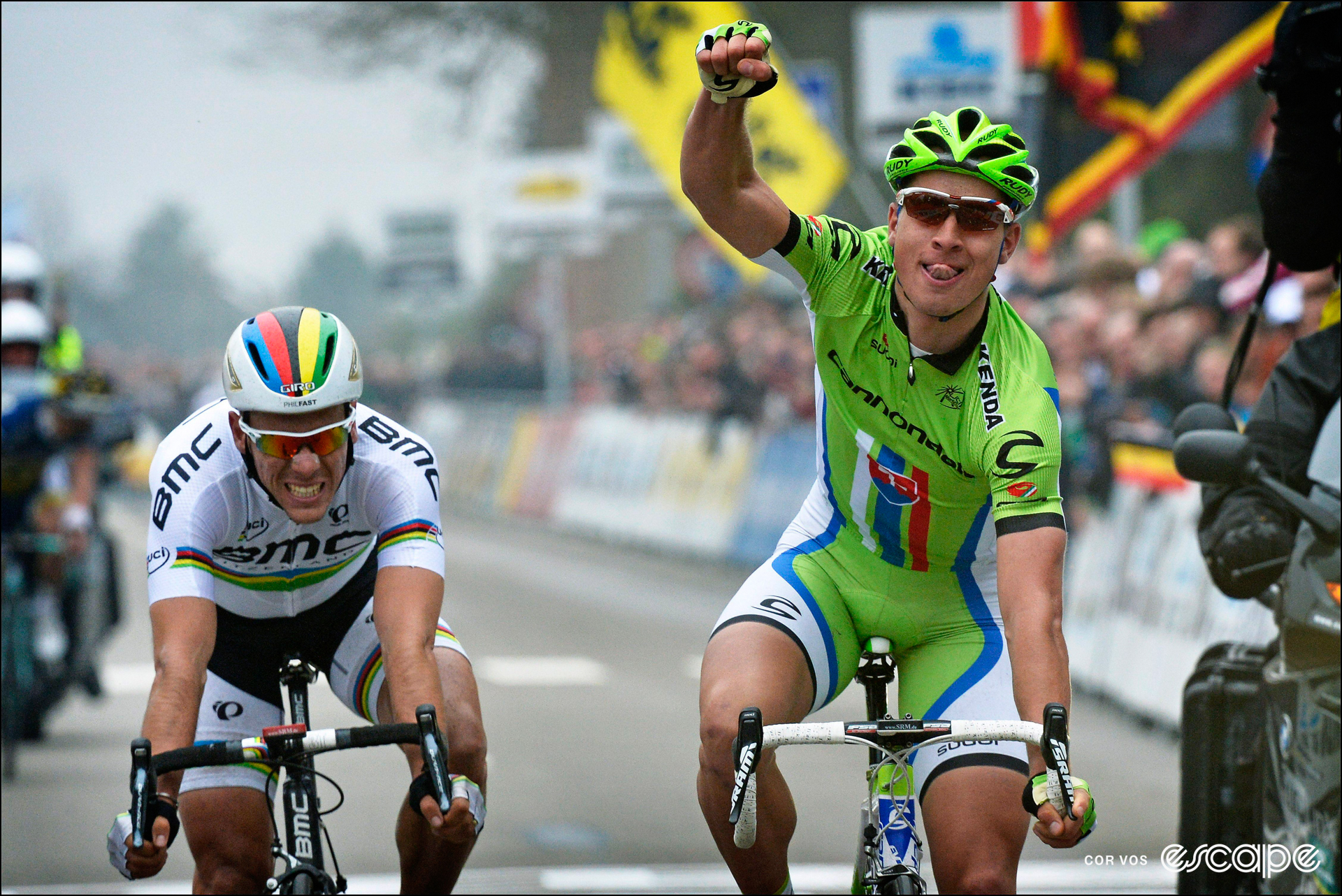 Peter Sagan celebrates winning the 2013 Brabantse Pijl with his tongue out, one fist in the air, and world champ Philippe Gilbert grimacing in the background.