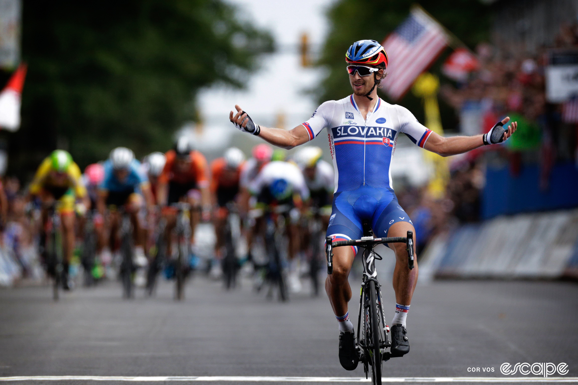 Peter Sagan celebrates winning the 2015 world road title with both arms outstretched to his side.