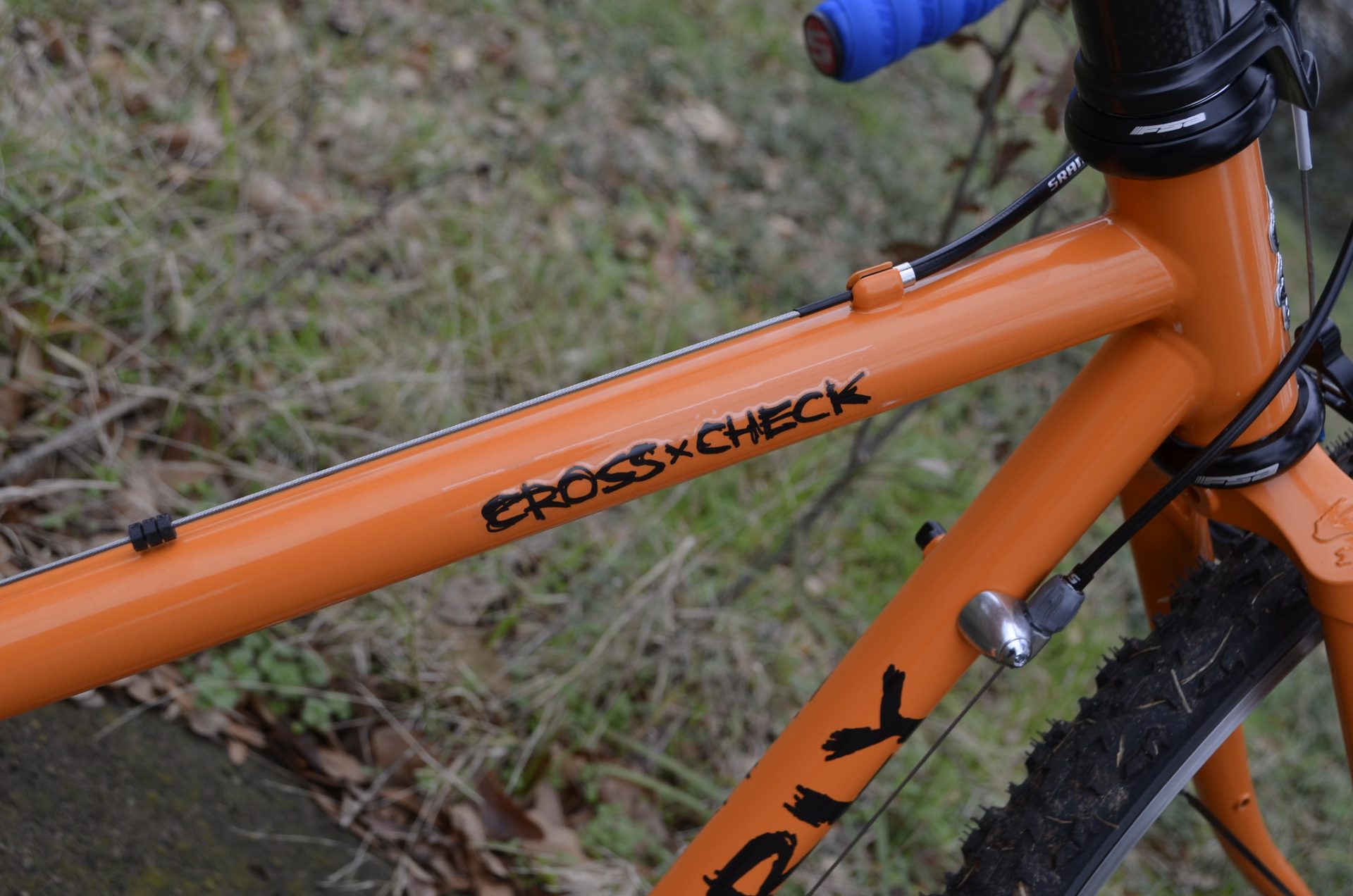 Detail shot of the top-tube of an Orange Surly Cross-check, showing the 'Cross-Check' logo. 