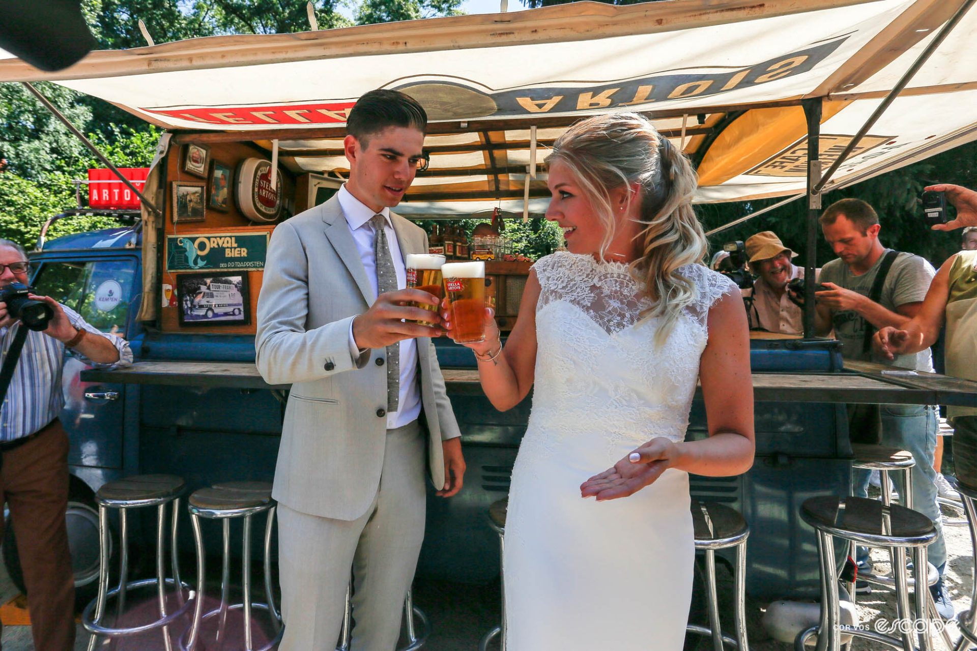 Wout van Aert wearing a nice suit and his wife Sarah De Bie, standing in front of a vintage beer truck with a Stella Artois each, clinking glasses while a bunch of photographers in t-shirts mill about. 