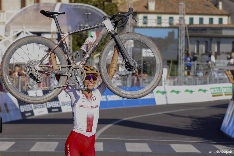 Kasia Niewiadoma holds her Canyon bike high after winning the 2023 Gravel World Championships