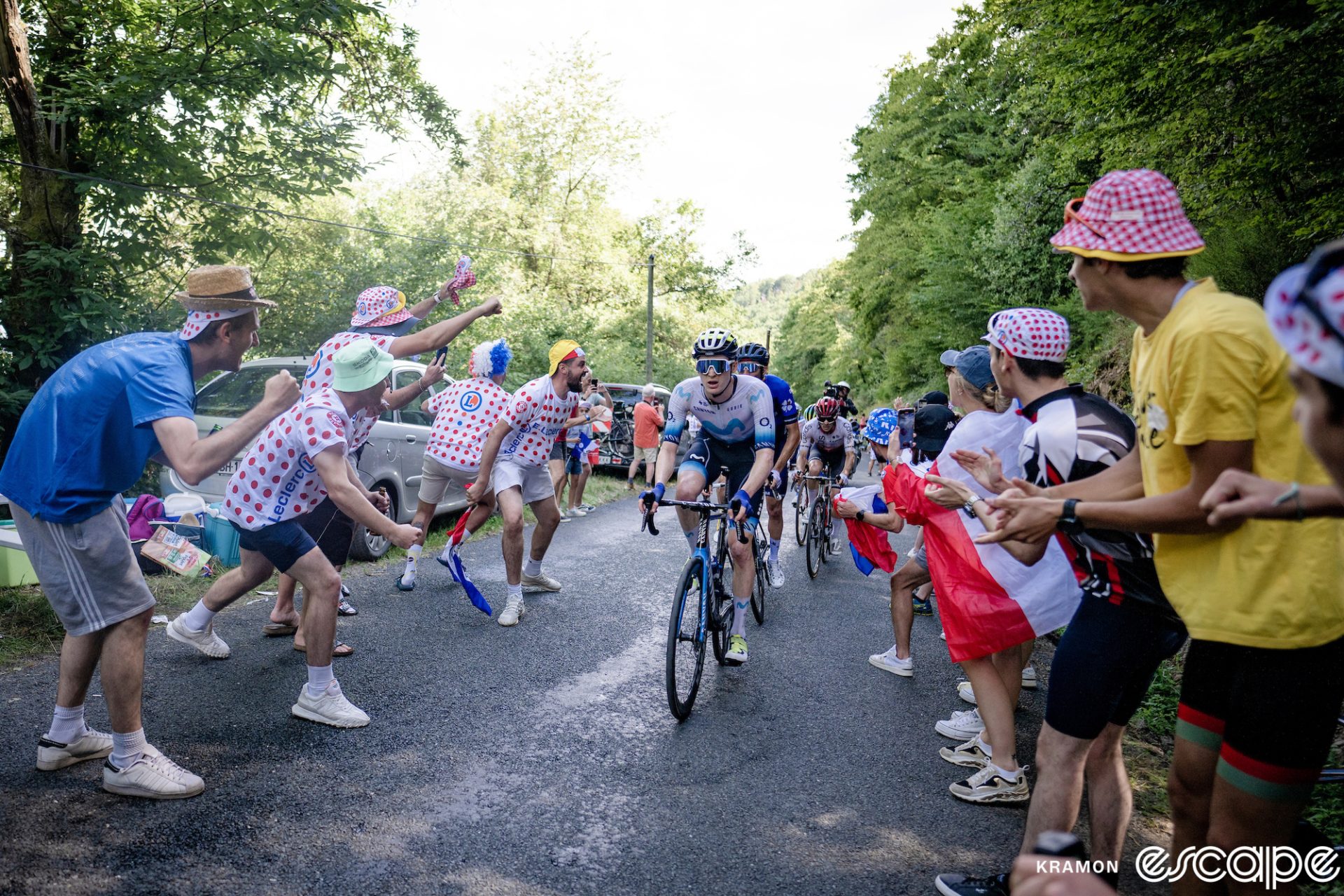 Matteo Jorgenson leads the breakaway on stage 12 of the 2023 Tour de France. He's climbing up a narrow road as fans, many dressed in polka-dot shirts and hats from the publicity caravan, lean in and cheer.