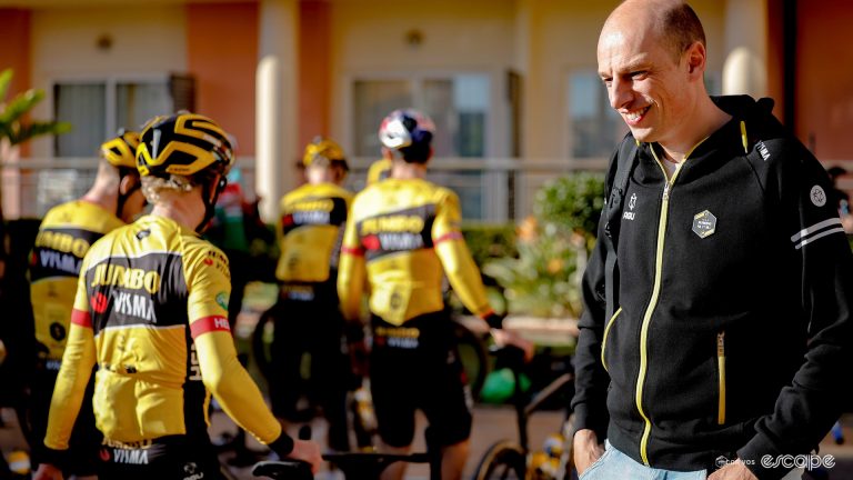 The photo shows Mathieu Heijboer Head of Performance pictured during wintertraining team Jumbo - Visma in Alicante, Spain. Mathieu is facing the camera while the Jumbo riders i the background have their backs to us.