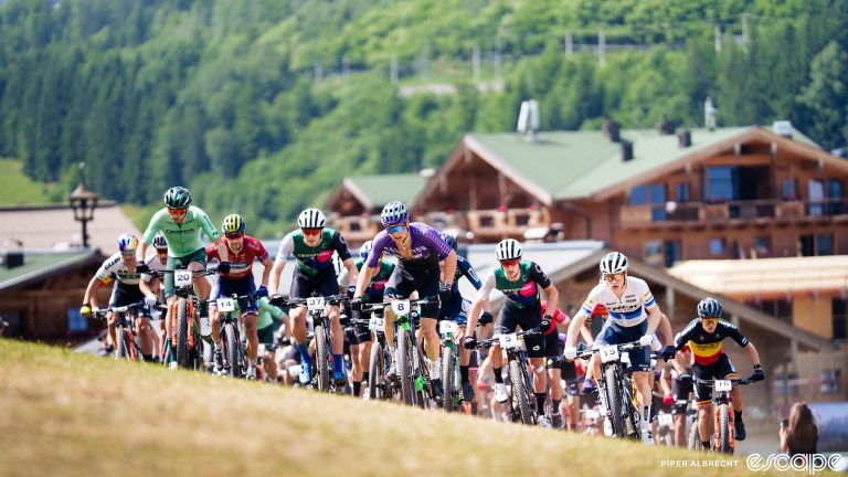 A crowd of cross-country racers surges up a hill at the Leogang World Cup race. They're spread out across an off-camber slope, sprinting out of the saddle out of the start village.