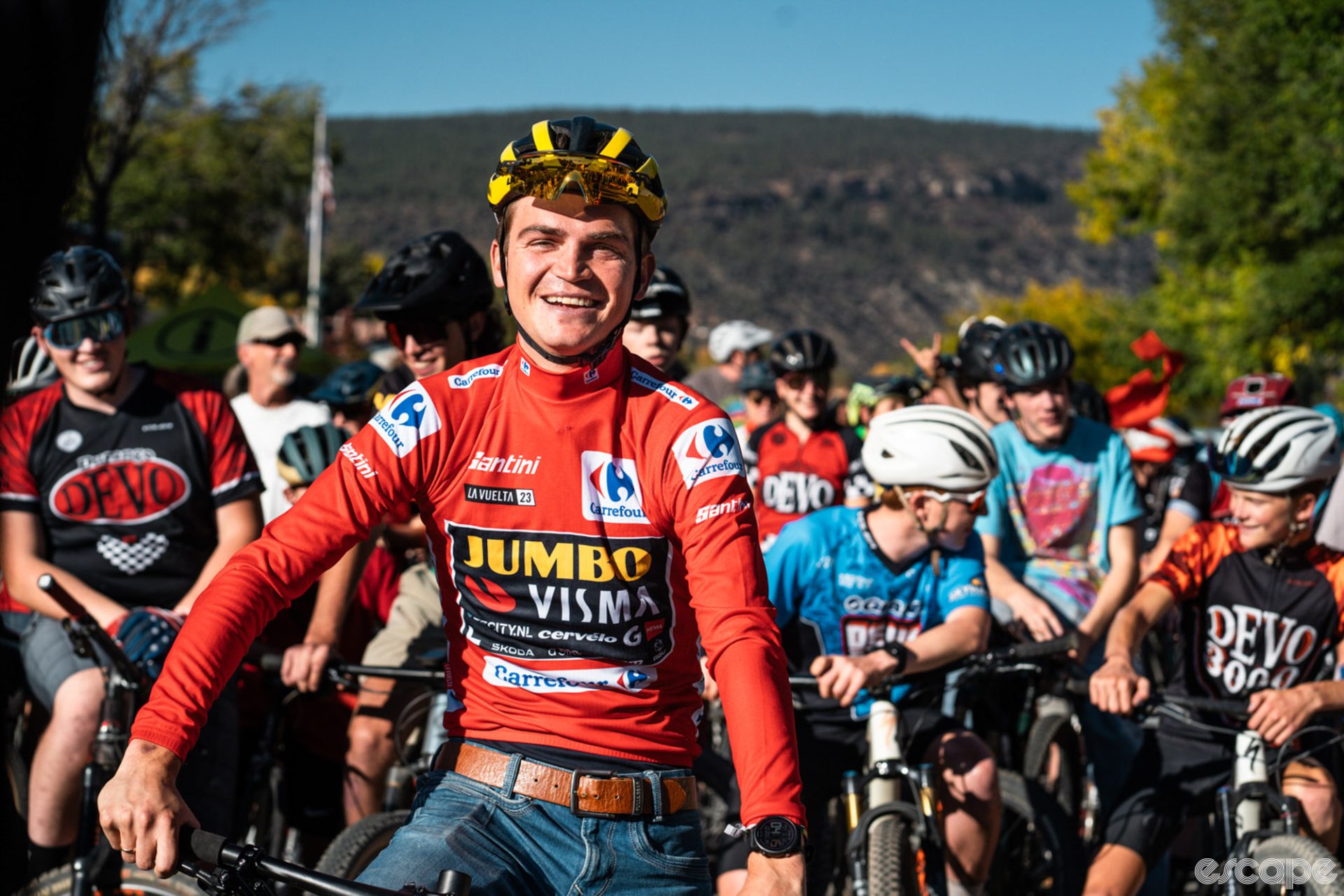 Kuss faces forward now as the ride starts. He's smiling in bright sunlight, while the crowd stretches into the distance behind him.