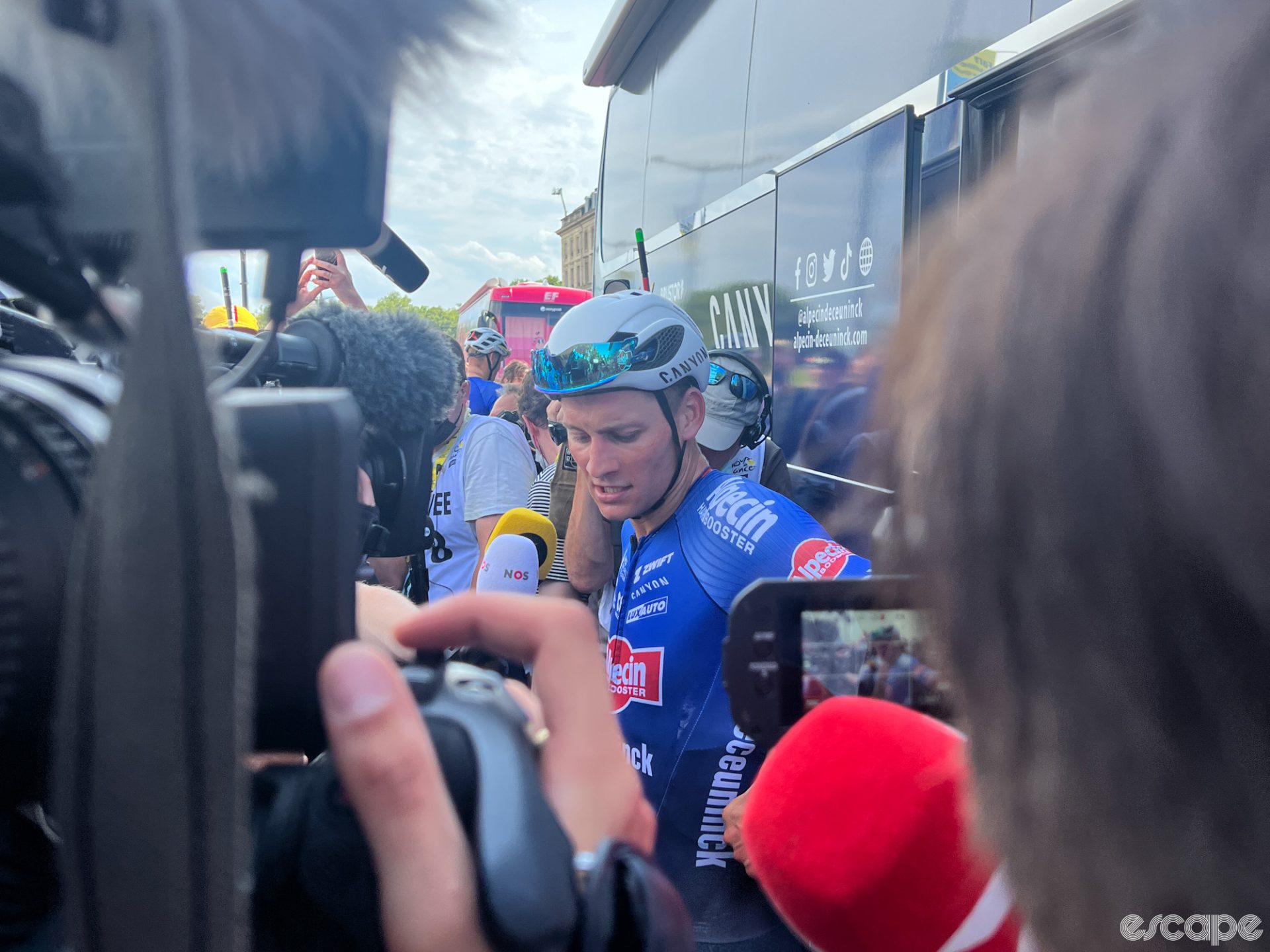 Mathieu van der Poel outside the Alpecin bus. He's seen from the perspective of someone inside the scrum of media.