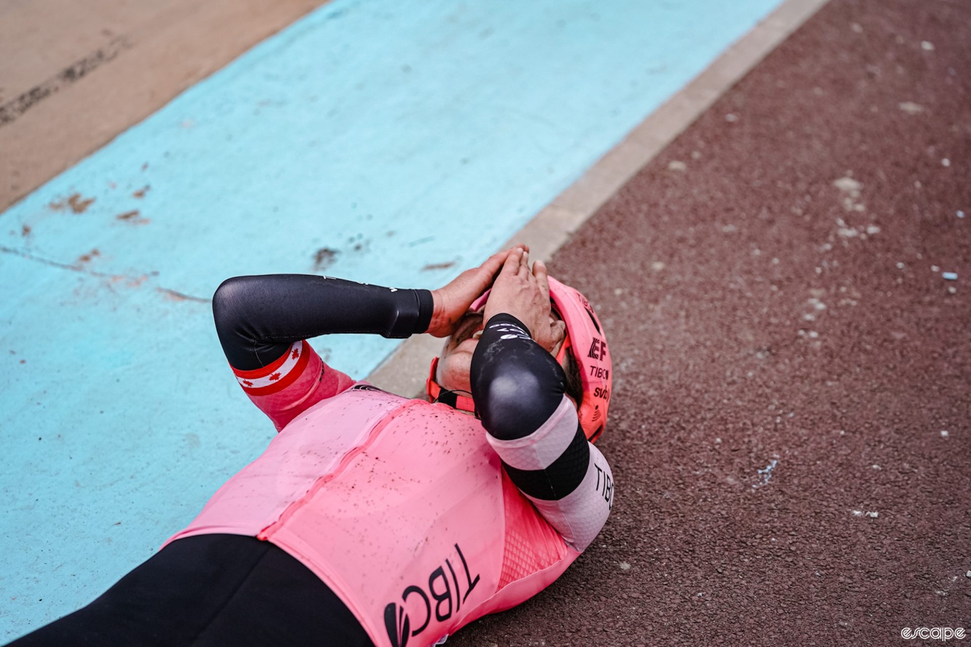 Alison Jackson laying on the ground, covers her face in disbelief after winning the 2023 edition of the Tour de France Femmes. 