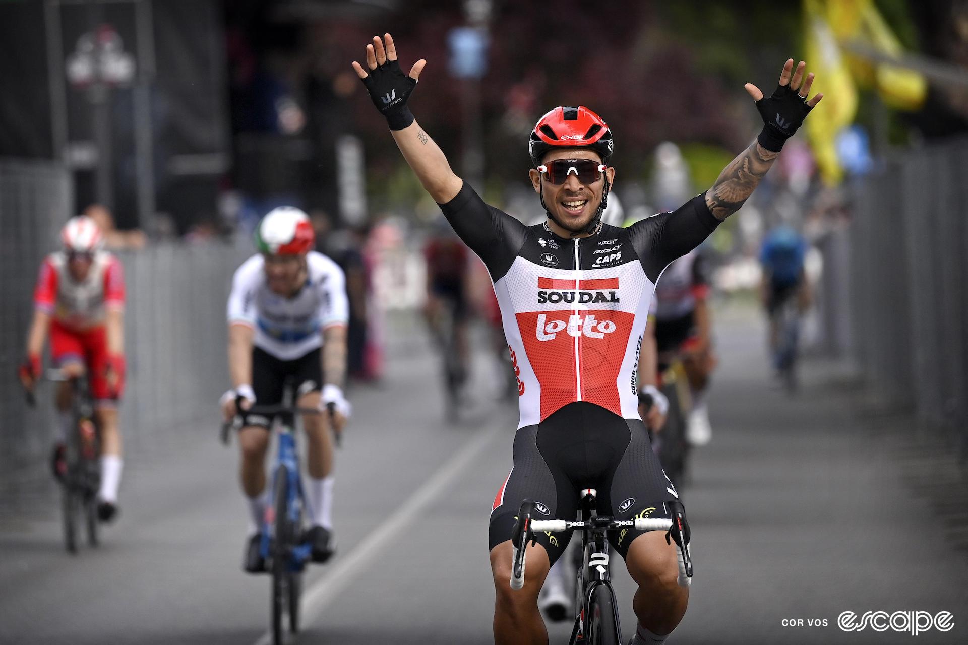 Caleb Ewan celebrates winning a Giro stage with two hands in the air.