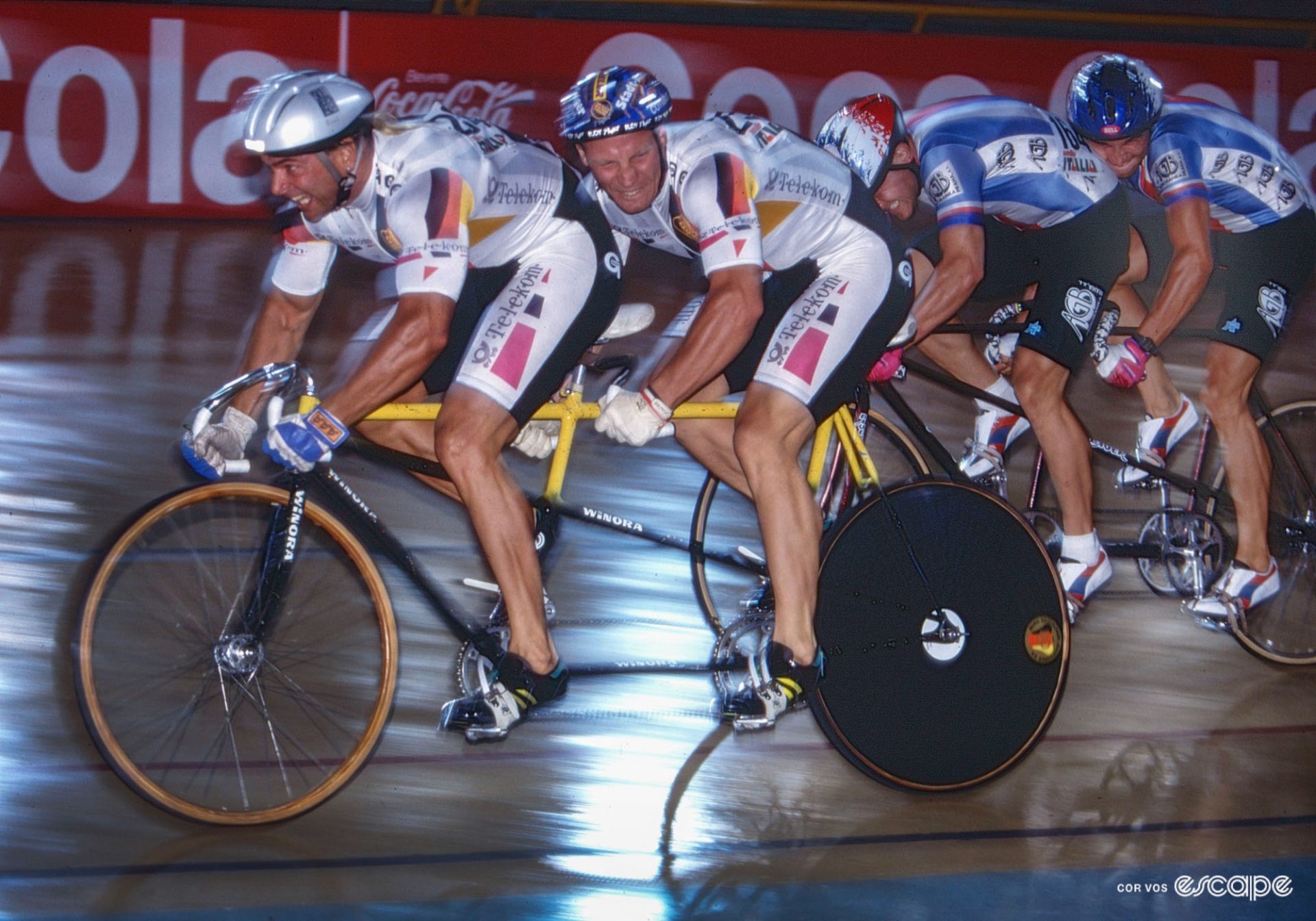 Two teams of tandem riders, both grimacing enormously and pushing with enormous effort.