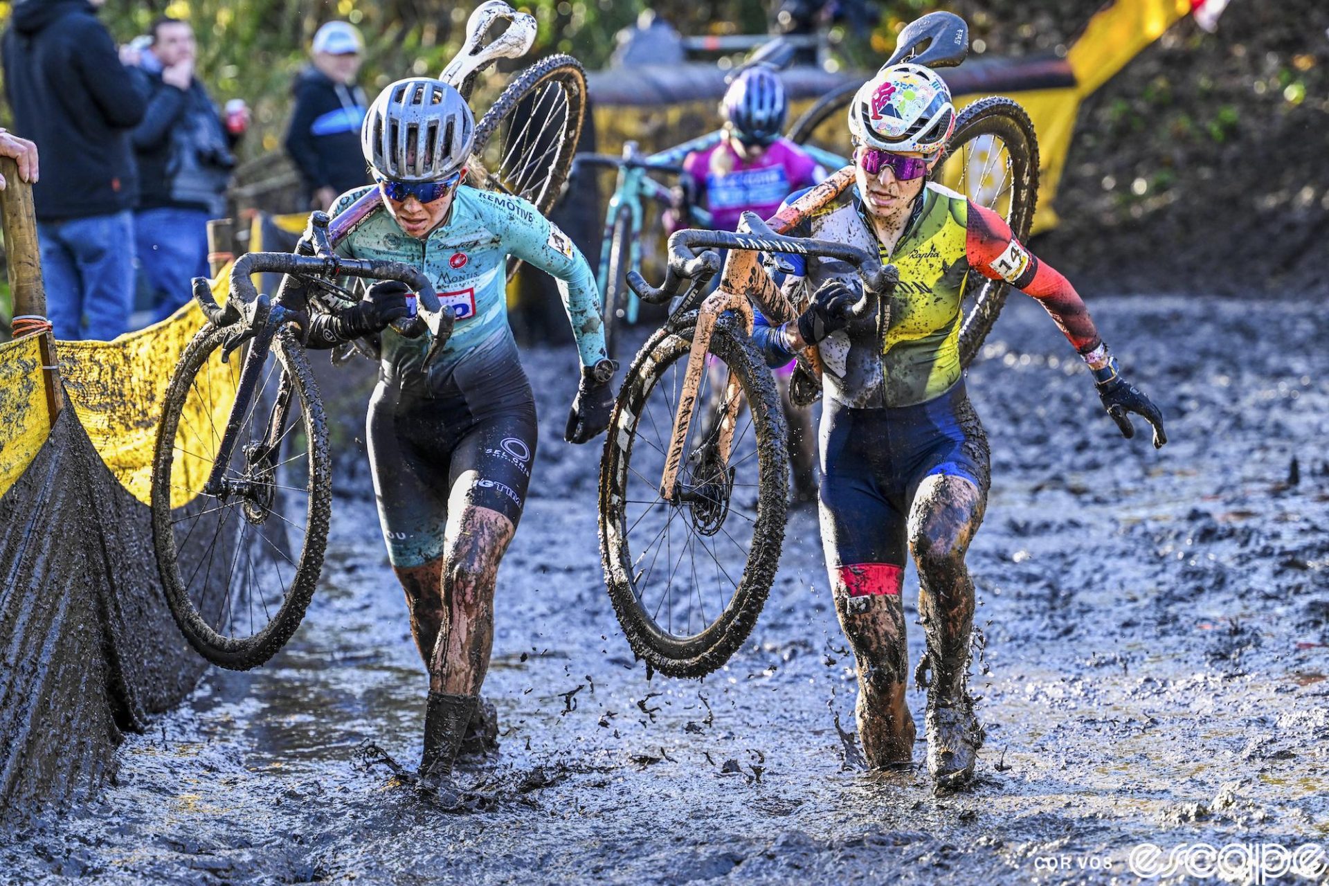 Amandine Fouquenet and Francesca Baroni shoulder their bikes and run through soupy mud during the women's Superprestige round in Niel. 