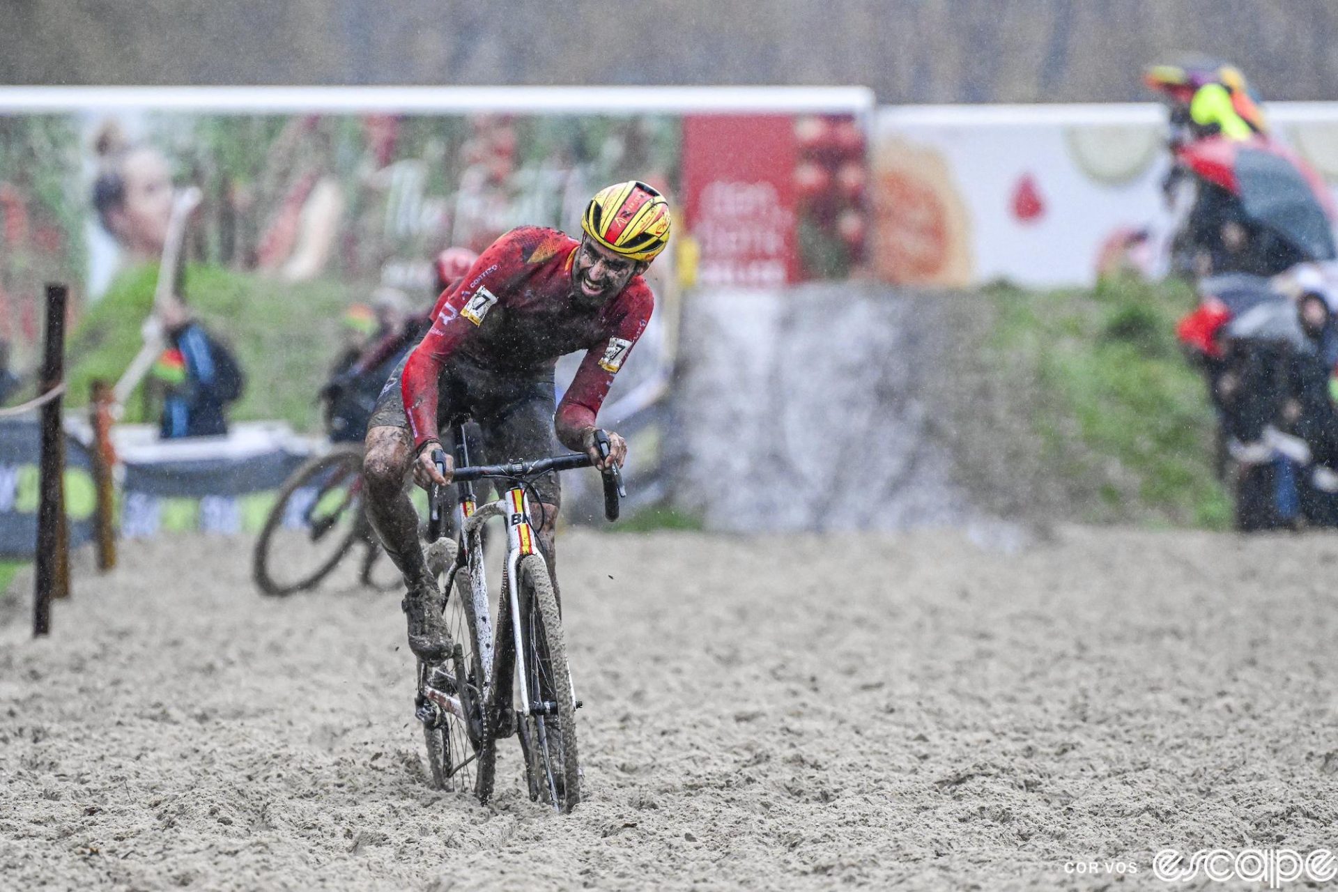 Felipe Orts grimaces as he leans his bike for balance while riding in the sand pit. The sand is deep, almost up to his rear derailleur pulley cage.