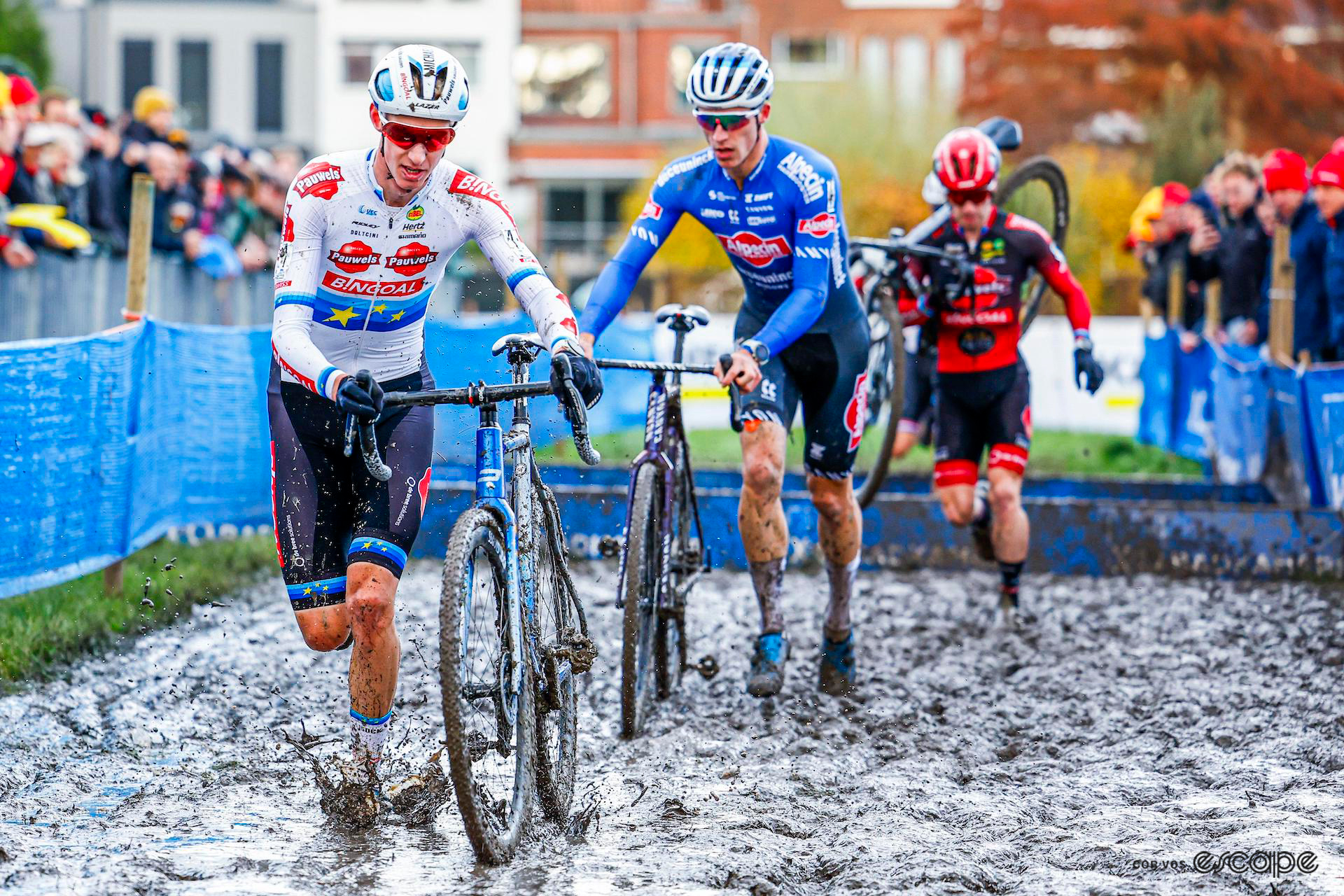 Michael Vanthourenhout leads the way single file through thick, wet mud, on foot with his bike alongside him during X20 Trofee Kortrijk.