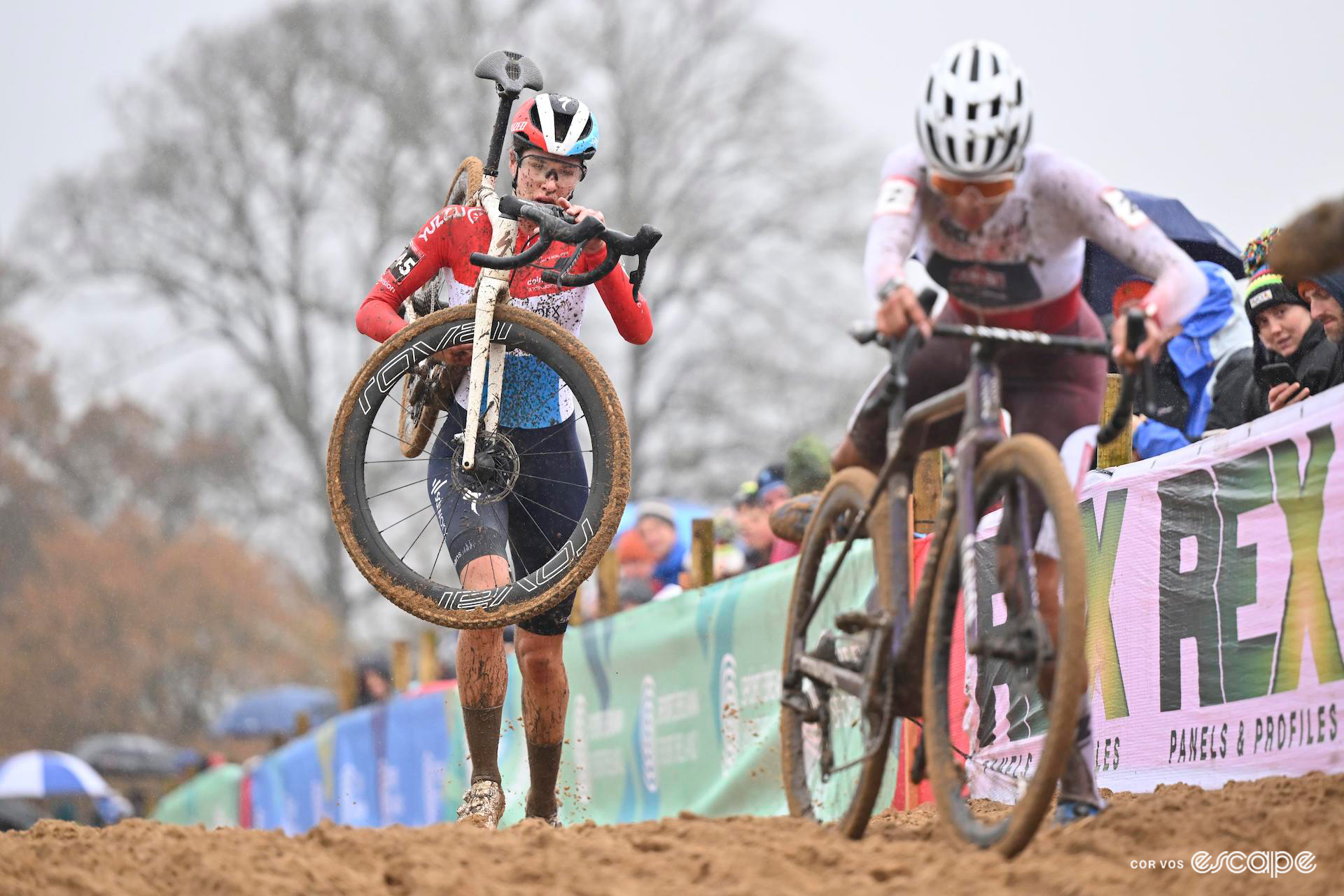 Ceylin del Carmen Alvarado, in the white and red jersey of overall World Cup leader, remounts her bike at the end of the sand section of CX World Cup Dublin, with Marie Schreiber a few metres behind, her bike on her shoulder.