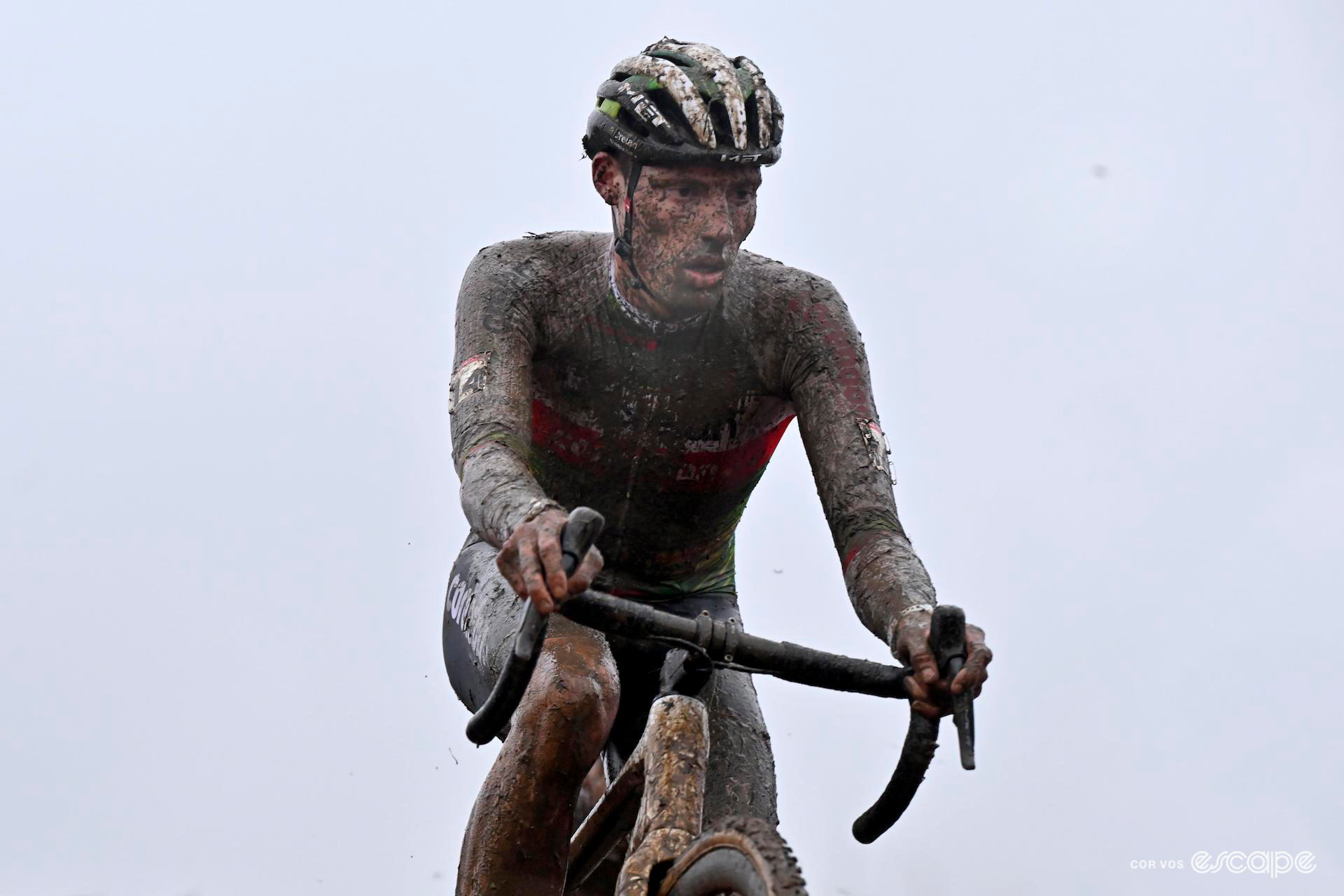 Covered head to toe in mud, Joran Wyseure of Crelan-Corendon looks focused and/or exhausted during CX World Cup Dublin, a grey overcast sky overhead.