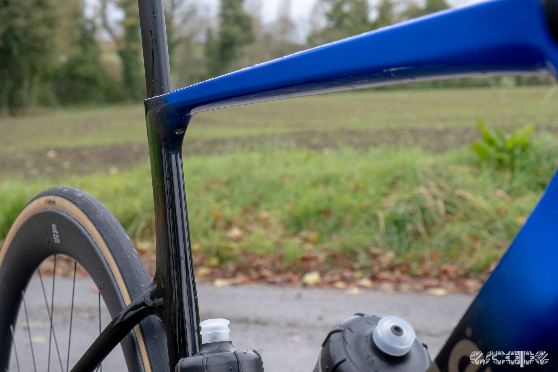 The photo shows the tapering top tube and aero profiled seat tube on a new Cannondale SuperSix Evo Hi-Mod 2 frame with Ultegra Di2 HollowGram and R-SL 50 wheelset pictured along a country lane with a ploughed and seeded field in the background.