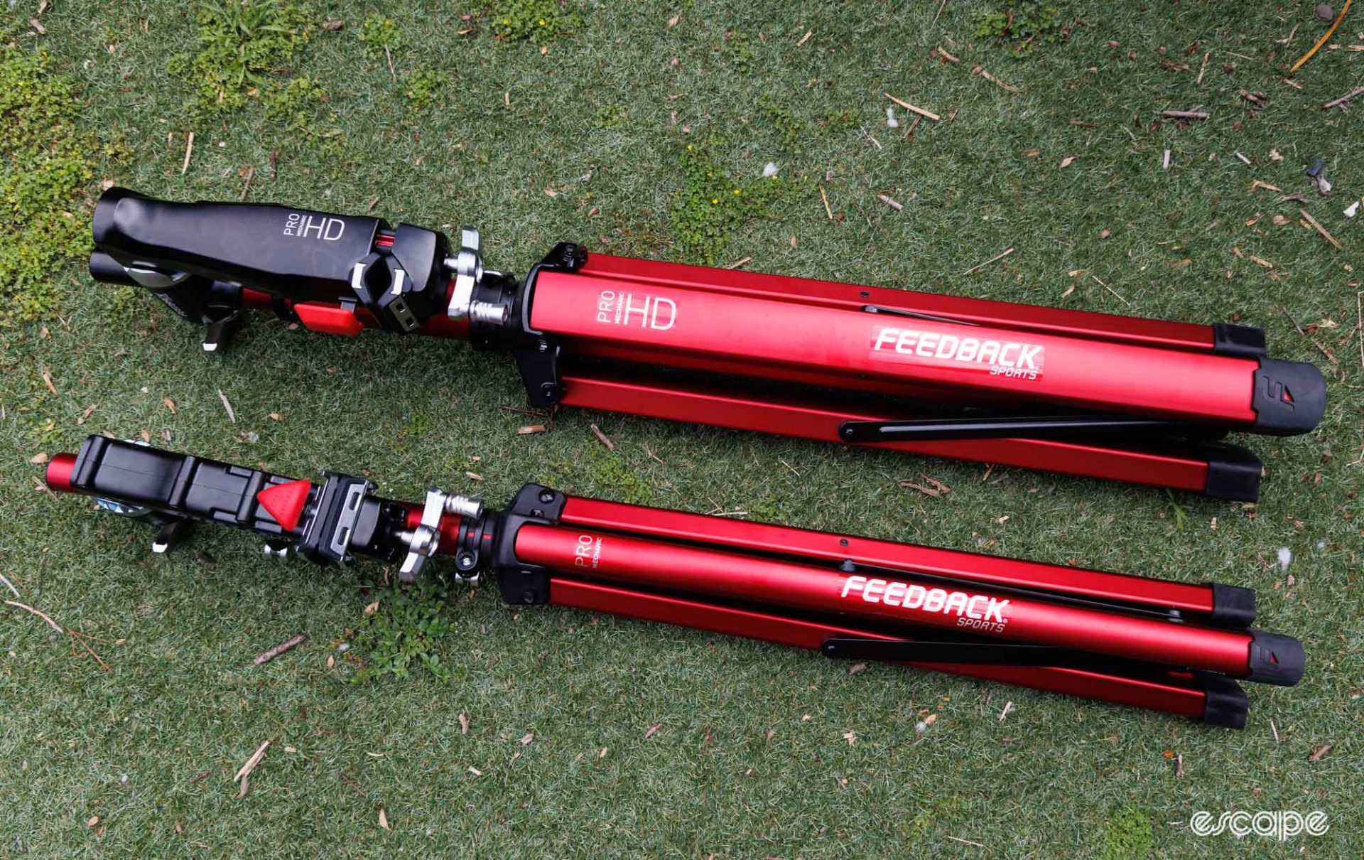 Duplicated photo from above. Feedback Sports Pro Mechanic and Pro Mechanic HD repair stands folded and on the ground. 