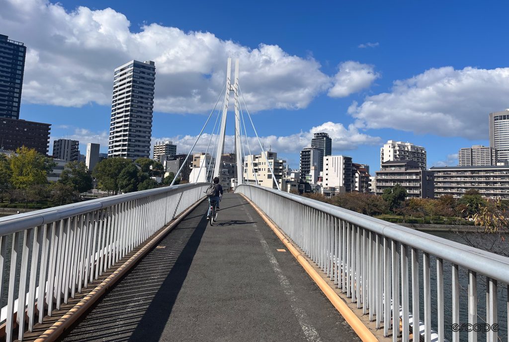 A cyclist rides over a bridge in Osaka.