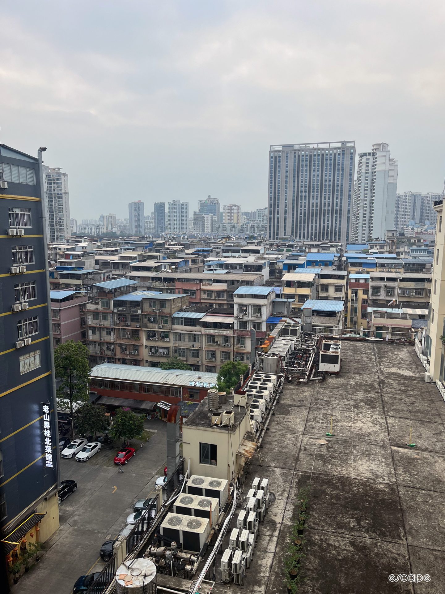 Nanning rooftops seen from a tall window against a hazy grey sky.