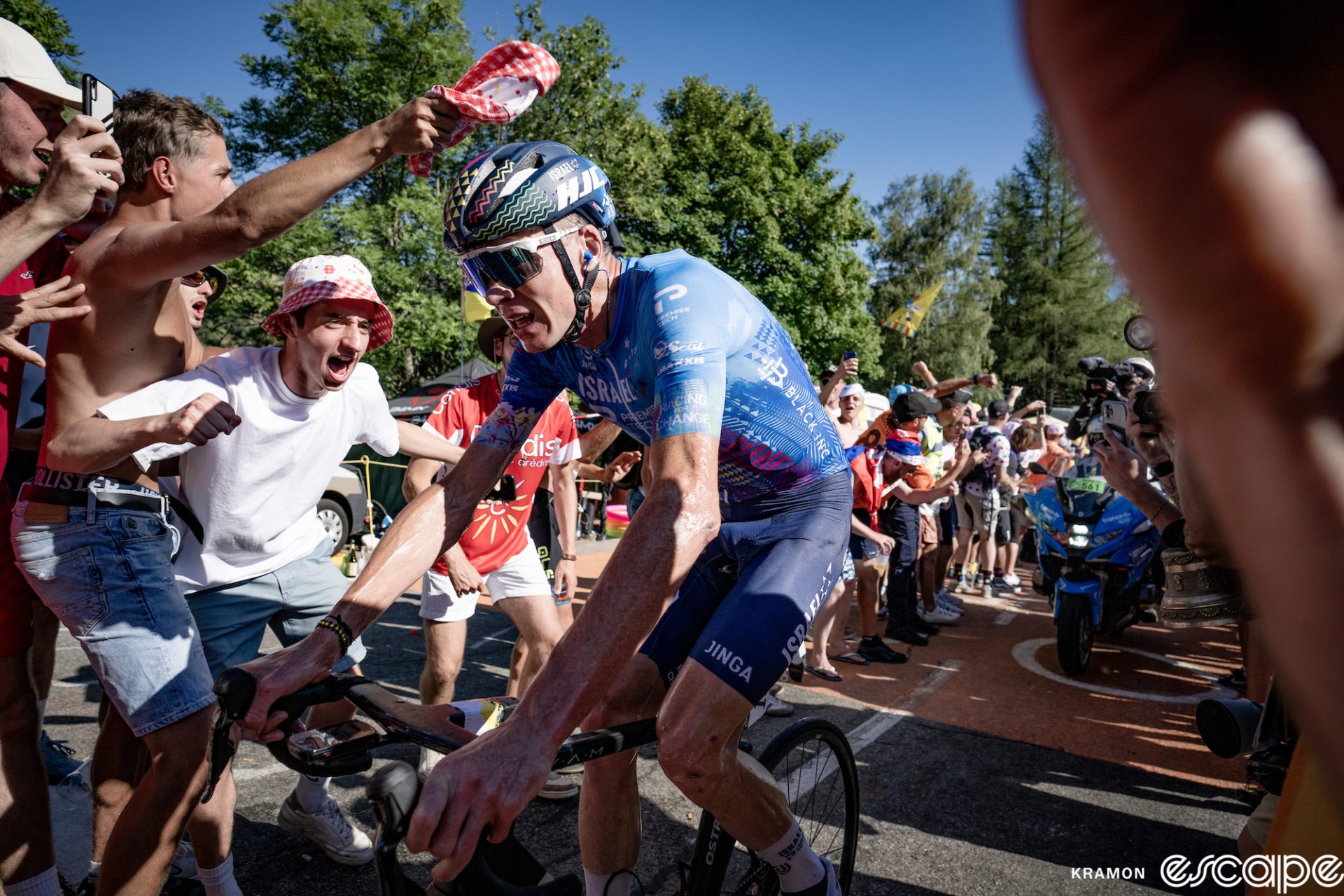 Chris Froome rides in the breakaway on Alpe d'Huez at the 2022 Tour de France, tailed by a motorbike and surrounded by hordes of cheering fans.