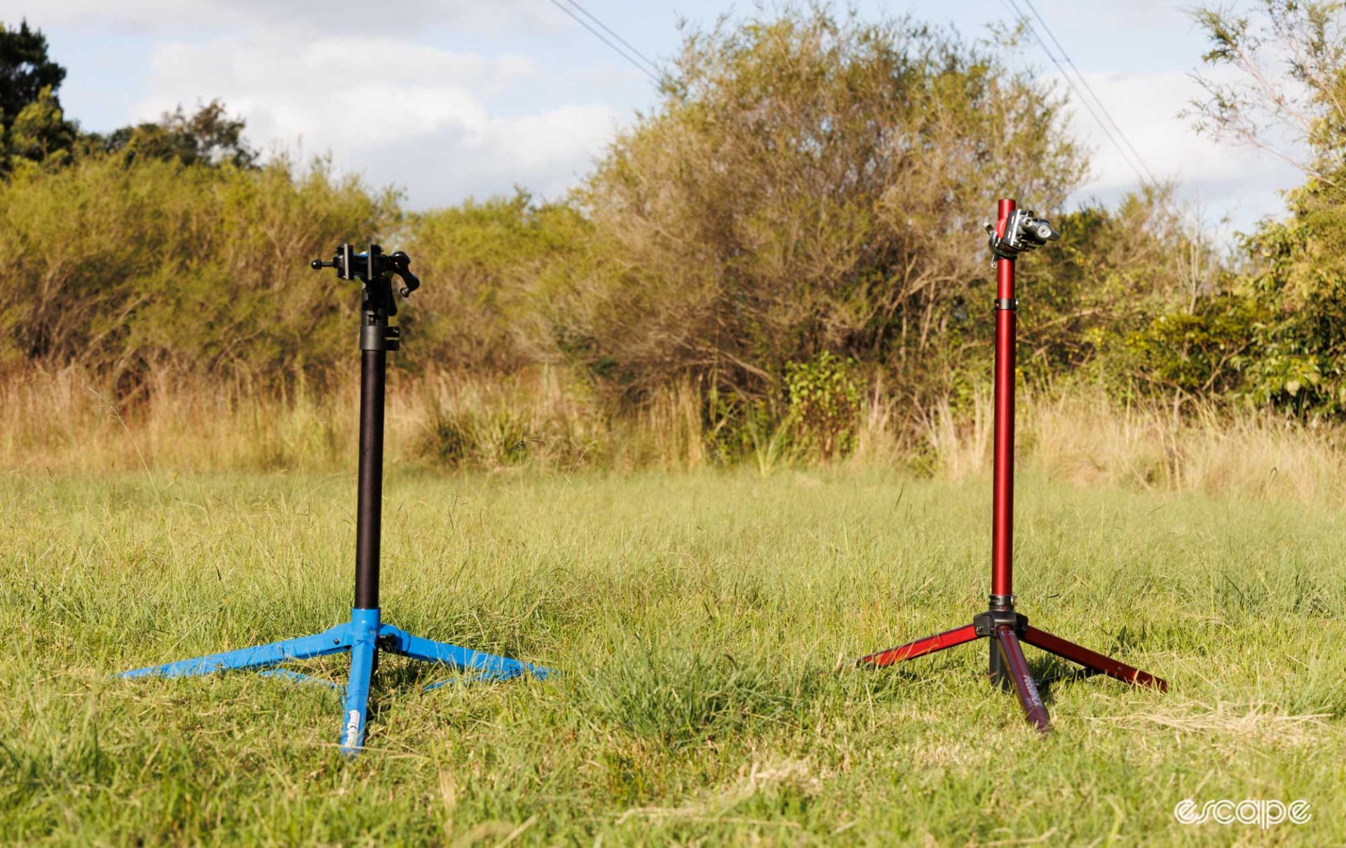 Park Tool PRS-26 (left) and Feedback Sports Pro Mechanic (right) stands in a grass field, set to the lowest heights. 