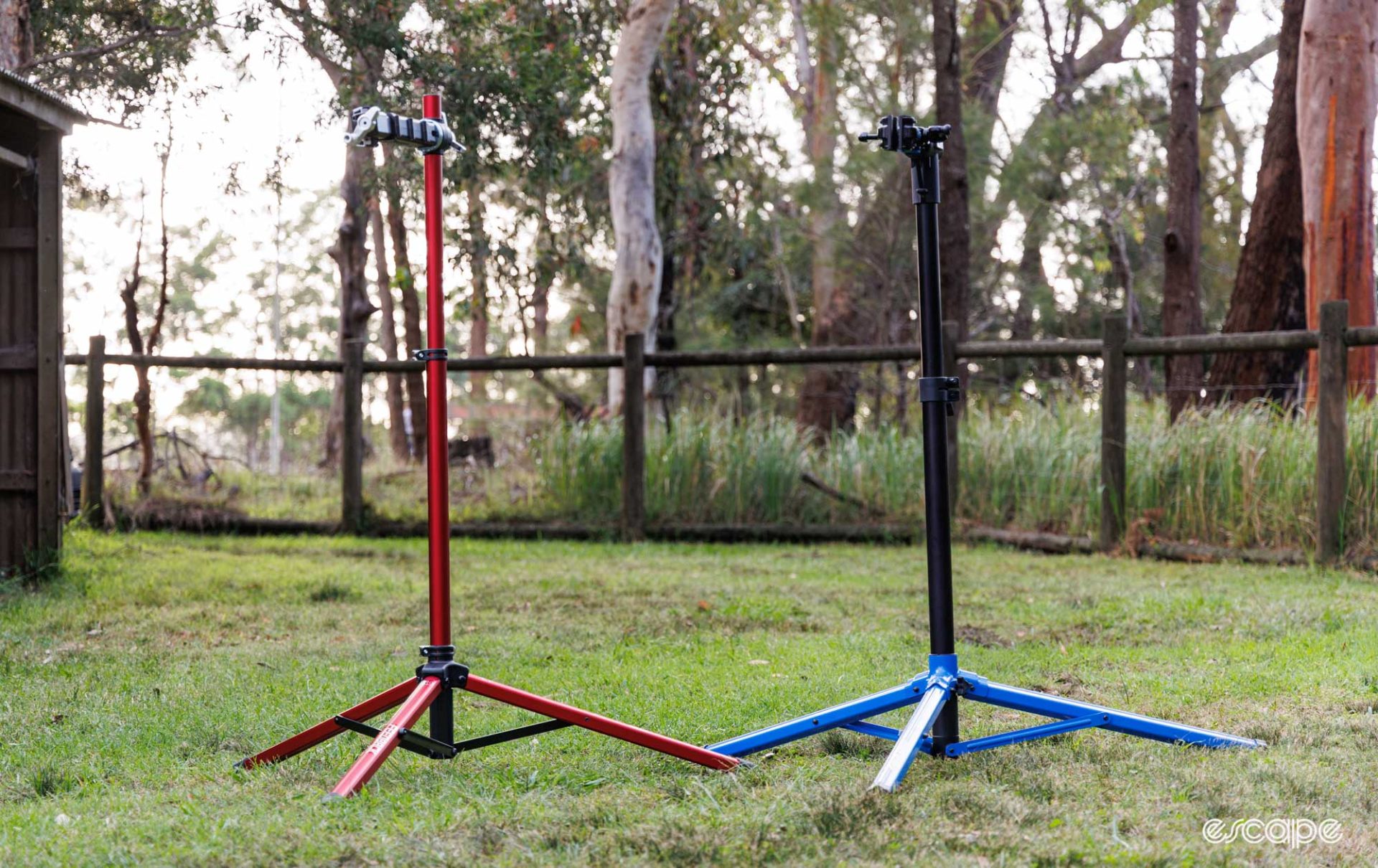 Feedback Sports Pro Mechanic and Park Tool PRS-26 repair stands unfolded and on a grass. field