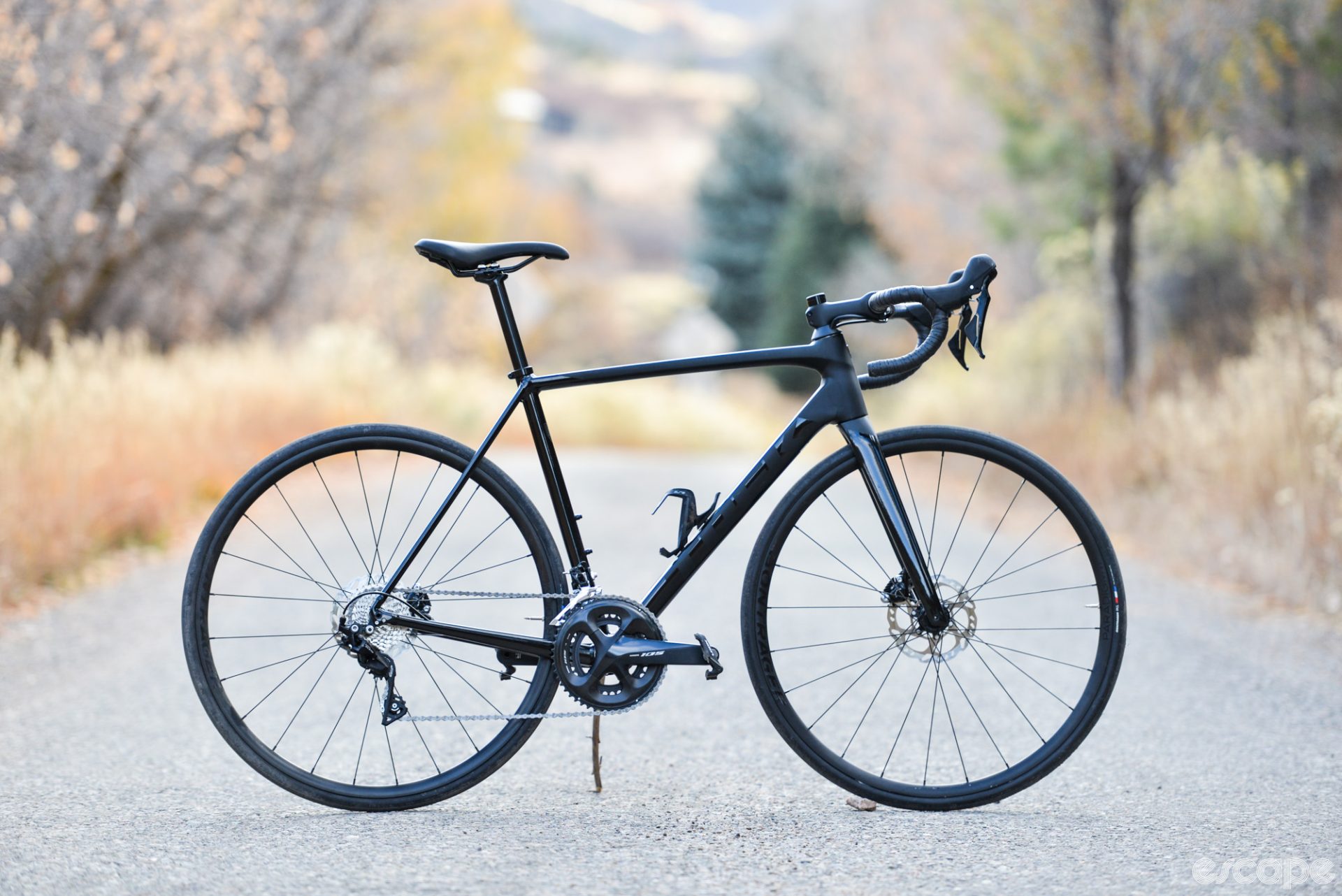 The Trek Emonda ALR5 in profile, with sleek black paint and blackout logos, all-grey Shimano 105 parts, and black Bontrager wheels and tires. In other words: black.