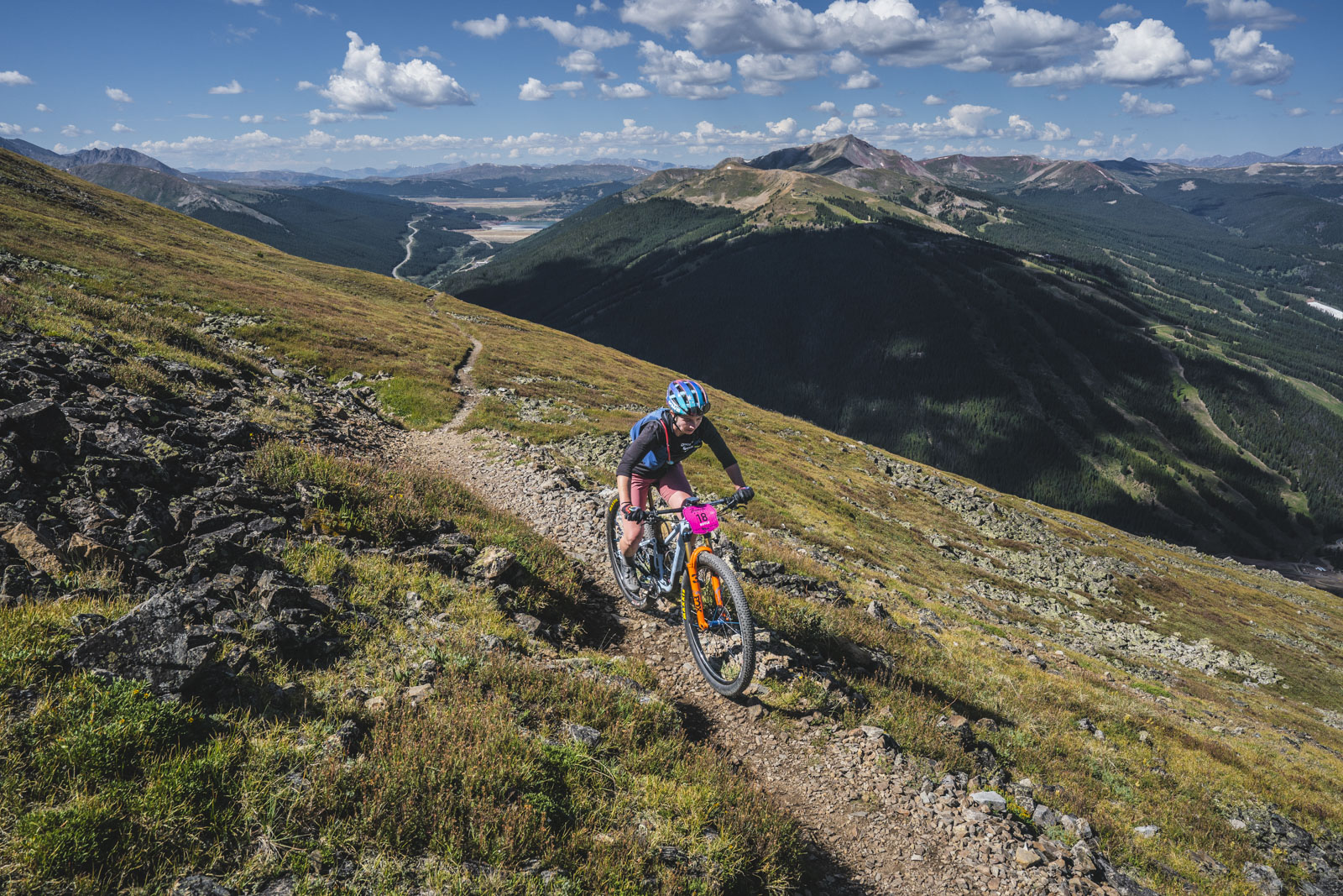 A female Breck Epic racer ascends a long singletrack on the Wheeler stage. She's all alone at high altitude above treeline.