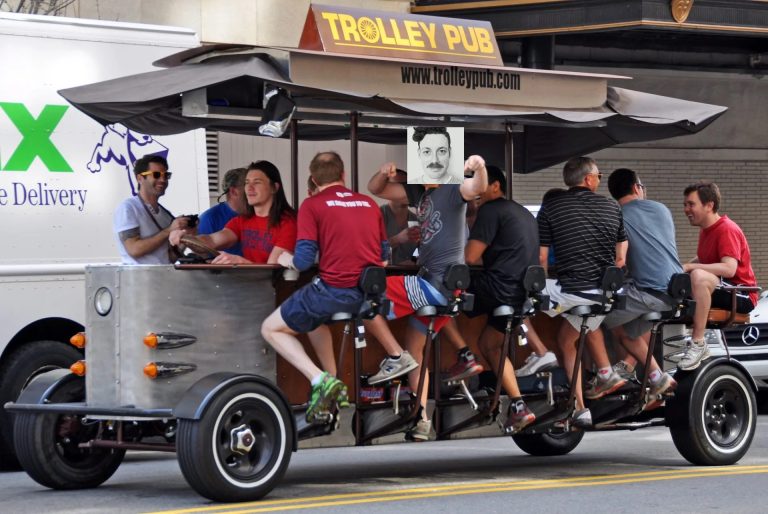 A photo of a group of men pedaling a beer bike. Iain's smiling mug is superimposed over one of them in an extremely crude photoshop job.