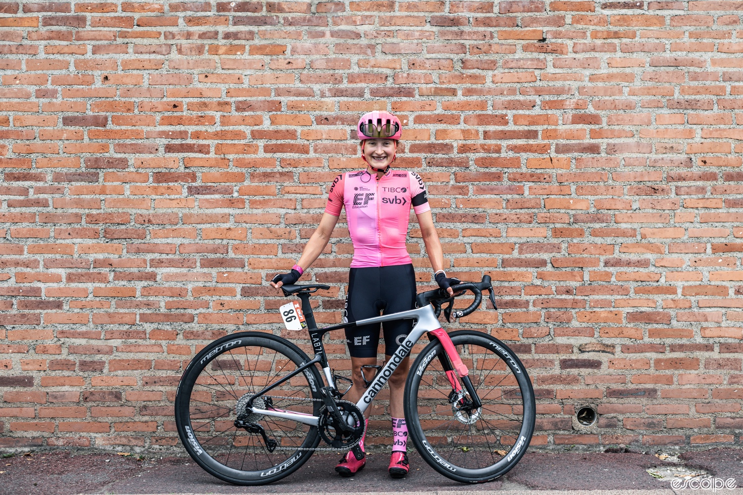 Vallieres stands in front of a brick wall with her Cannondale.
