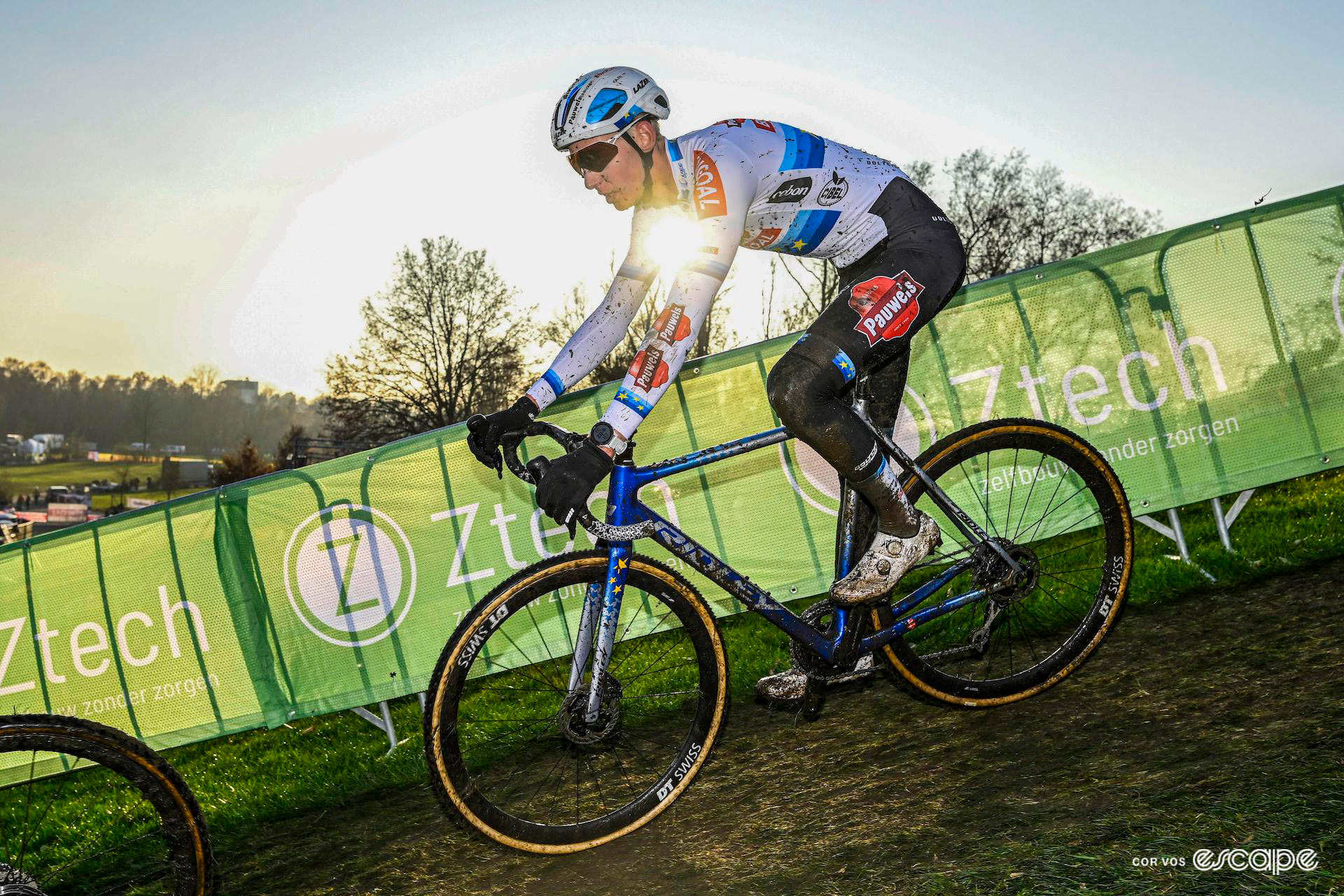 European champion Michael Vanthourenhout rides a grassy descent during Superprestige Boom, backlit by the low sun that's appearing under his arm.