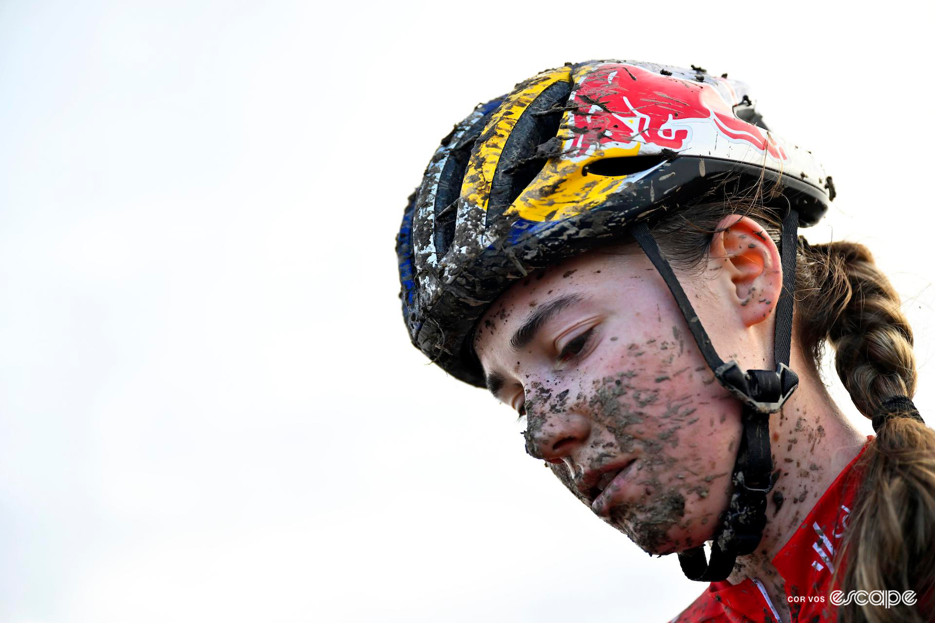 Close-up of Blanka Vas, her face and Red Bull-branded helmet splattered with mud, after Cyclocross World Cup Flamanville.