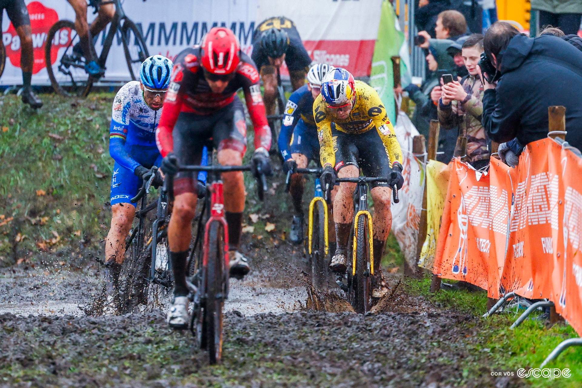 The elite men's front group ride through a muddy puddle during a very wet Exact Cross Essen.