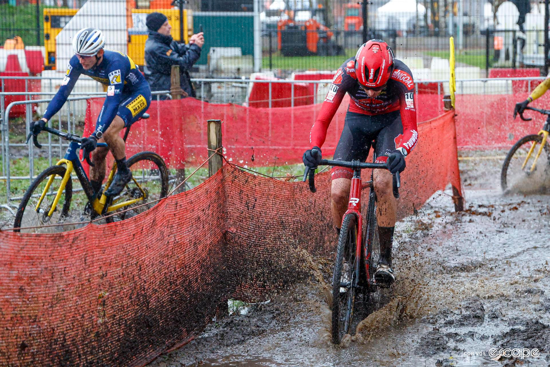 Yorben Lauryssen bypasses the pits as Victor van de Putte goes in for a bike change during a very wet and muddy Exact Cross Essen.