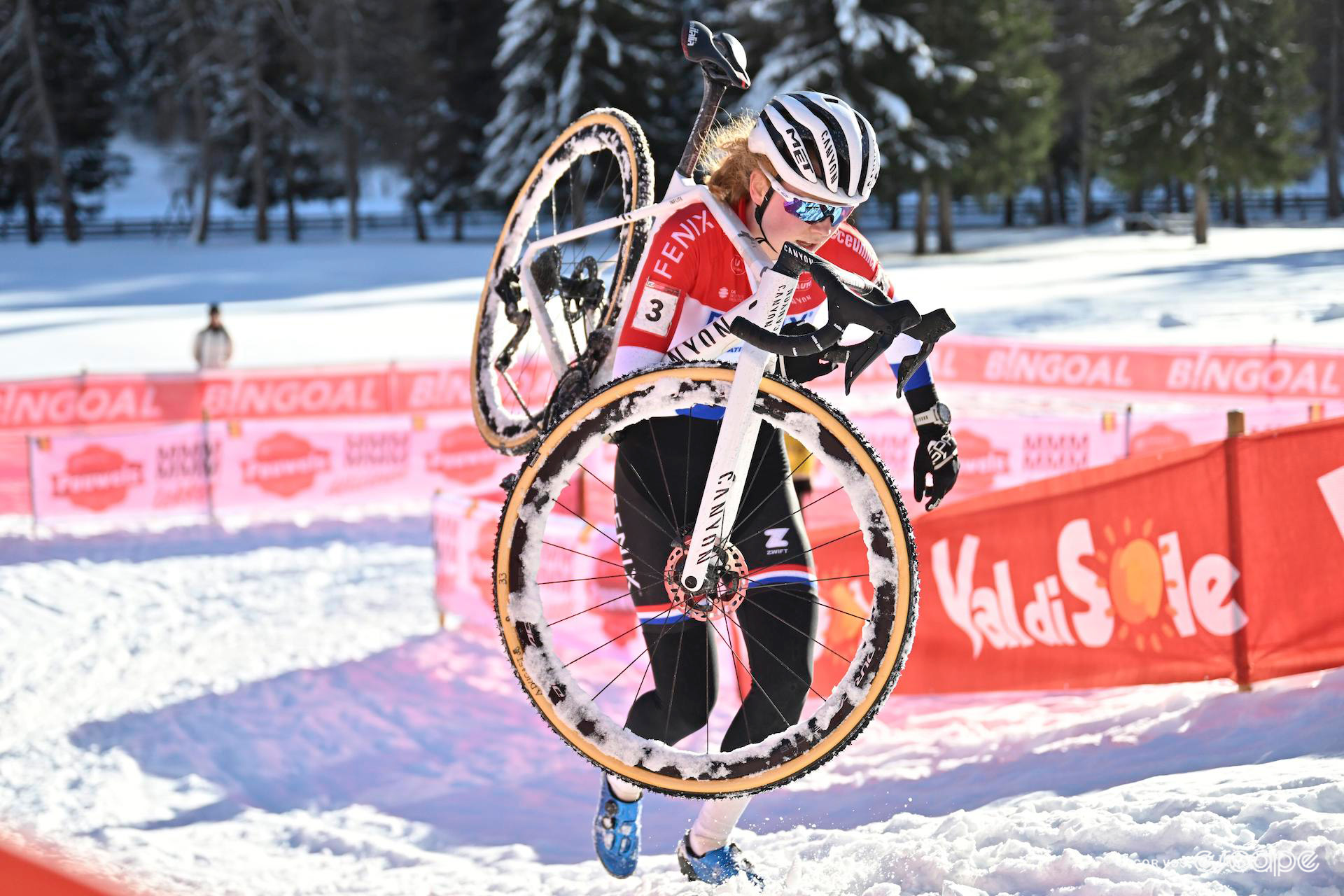 Dutch national champion Puck Pieterse carries her bike as she runs over the snow during UCI Cyclocross World Cup Val di Sole.