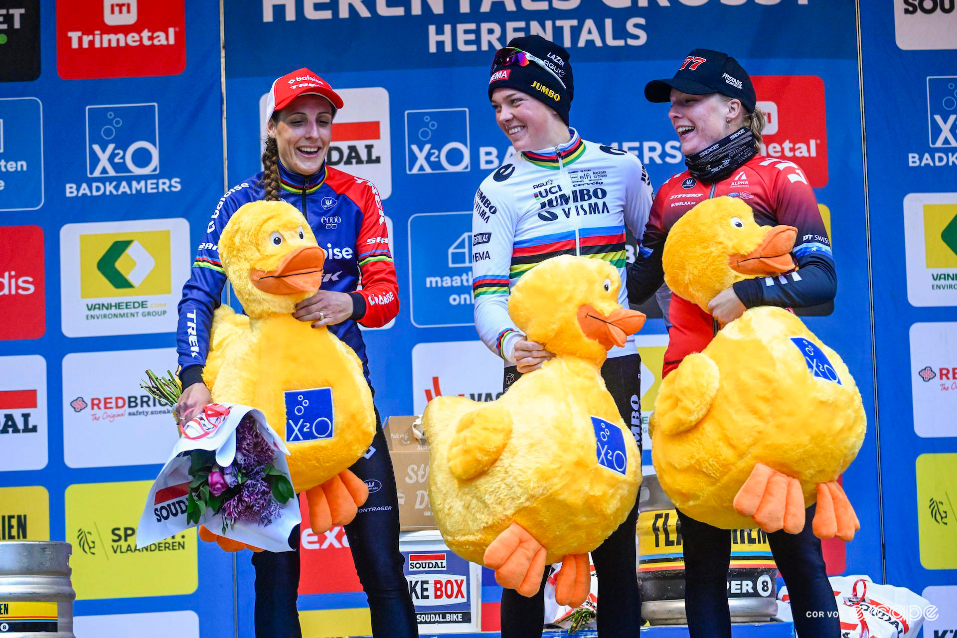 The elite women's podium of winner Fem van Empel, runner-up Lucinda Brand and third-place Annemarie Worst at X2O Trofee Herentals with their large X2O duck mascots.