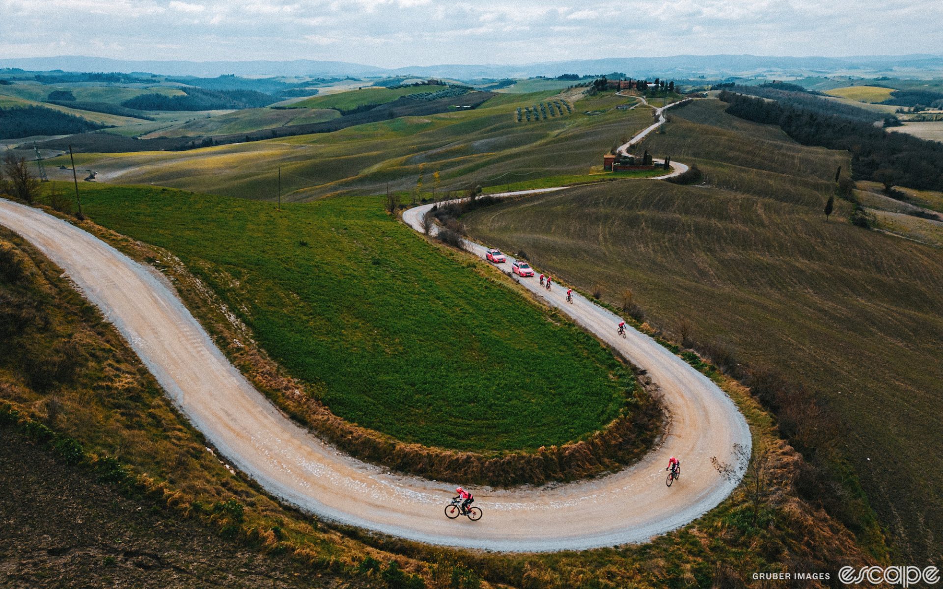 EF Education-Tibco-SVB riders recon Strade Bianche in March. They're on white gravel roads shown from above as the route snakes away amid vineyards and fields.