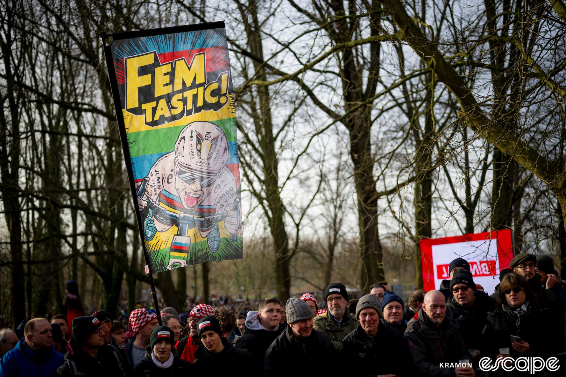 Fans at Gavere. ONe holds a large banner aloft that reads "Femtastic" and shows a cartoon Van Empel riding her bike in the superman position (legs out behind) with her tongue out.
