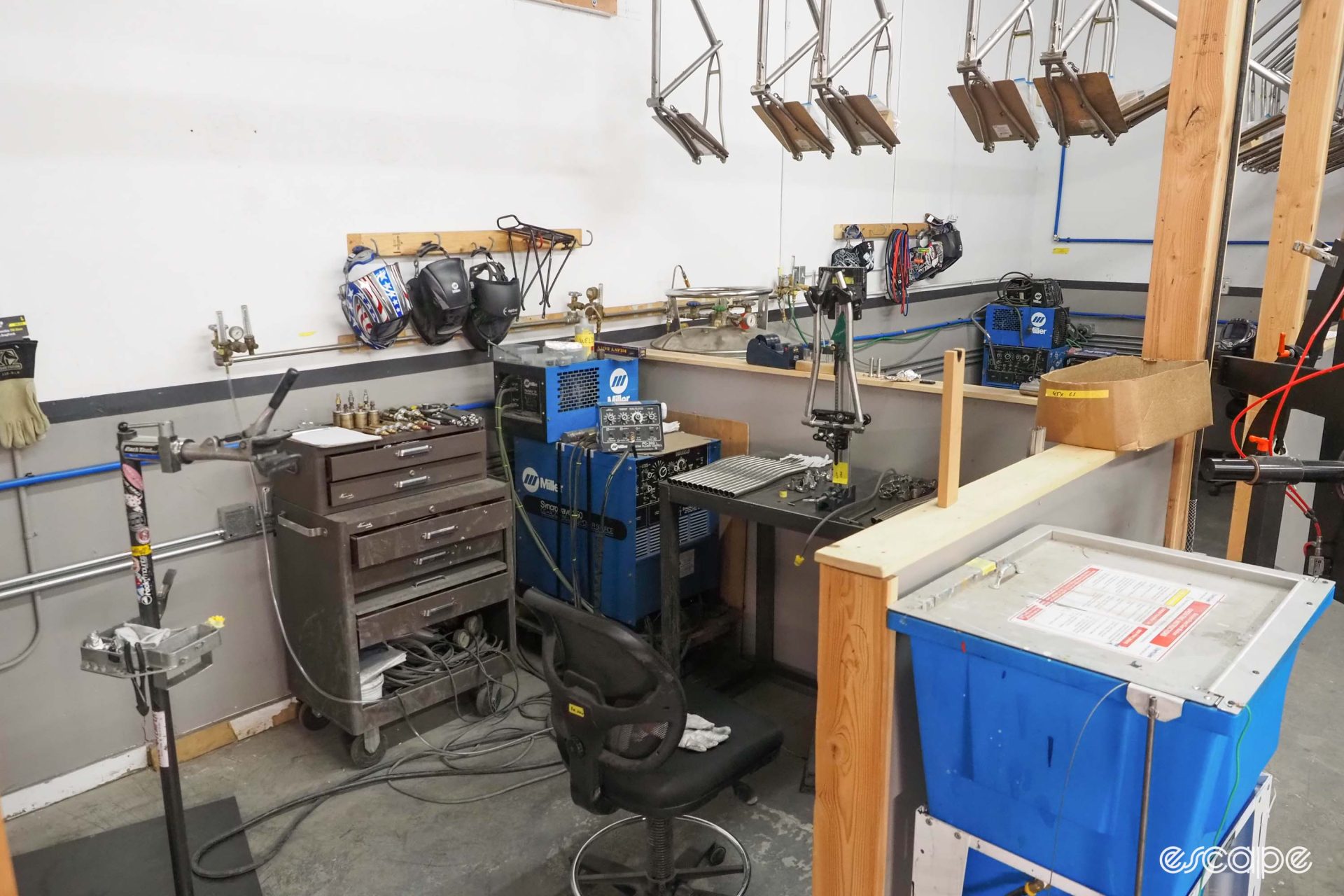 One of the TIG welding stations; it's a small affair with a frame jig on a small table and a standard office chair, accompanied by a tool case and welding equipment.
